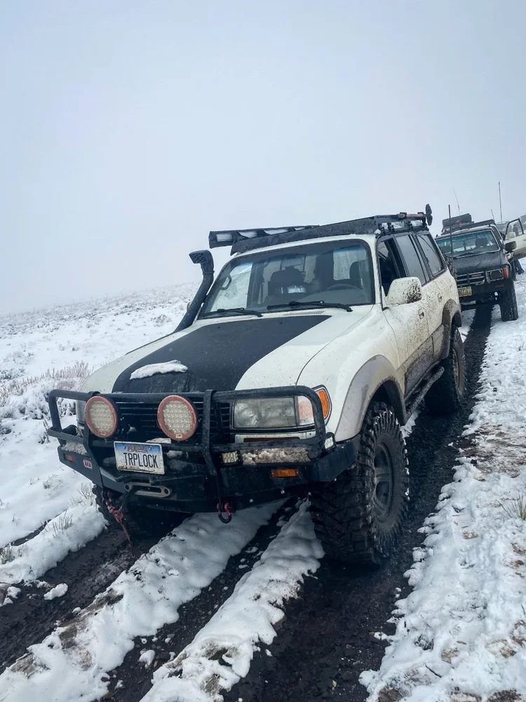 An 80 Series Land Cruiser driving inside deep, snow-filled ruts on the Dillon club run.
