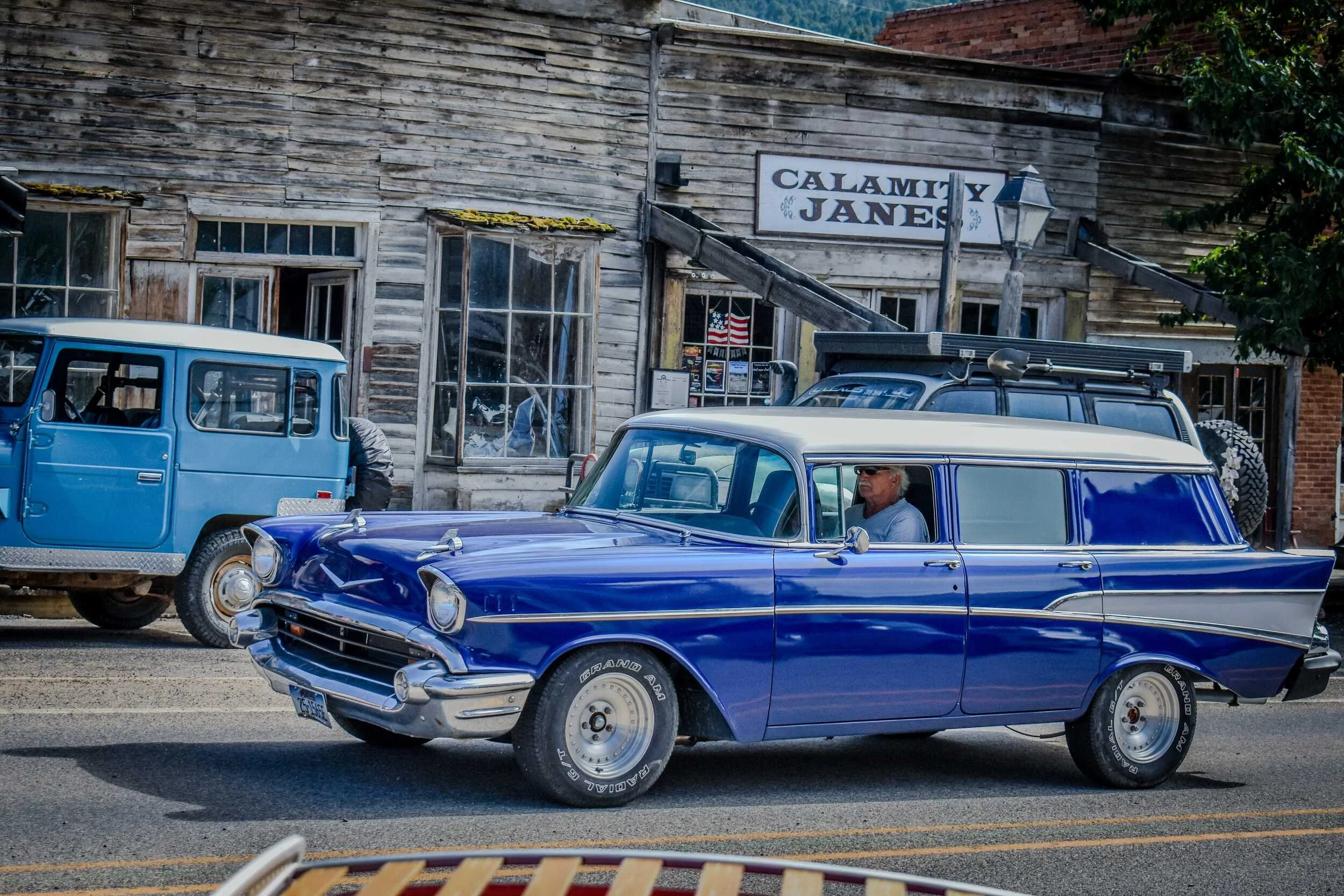 Blue and white vintage station wagon passing Calamity Jane's in Virginia City