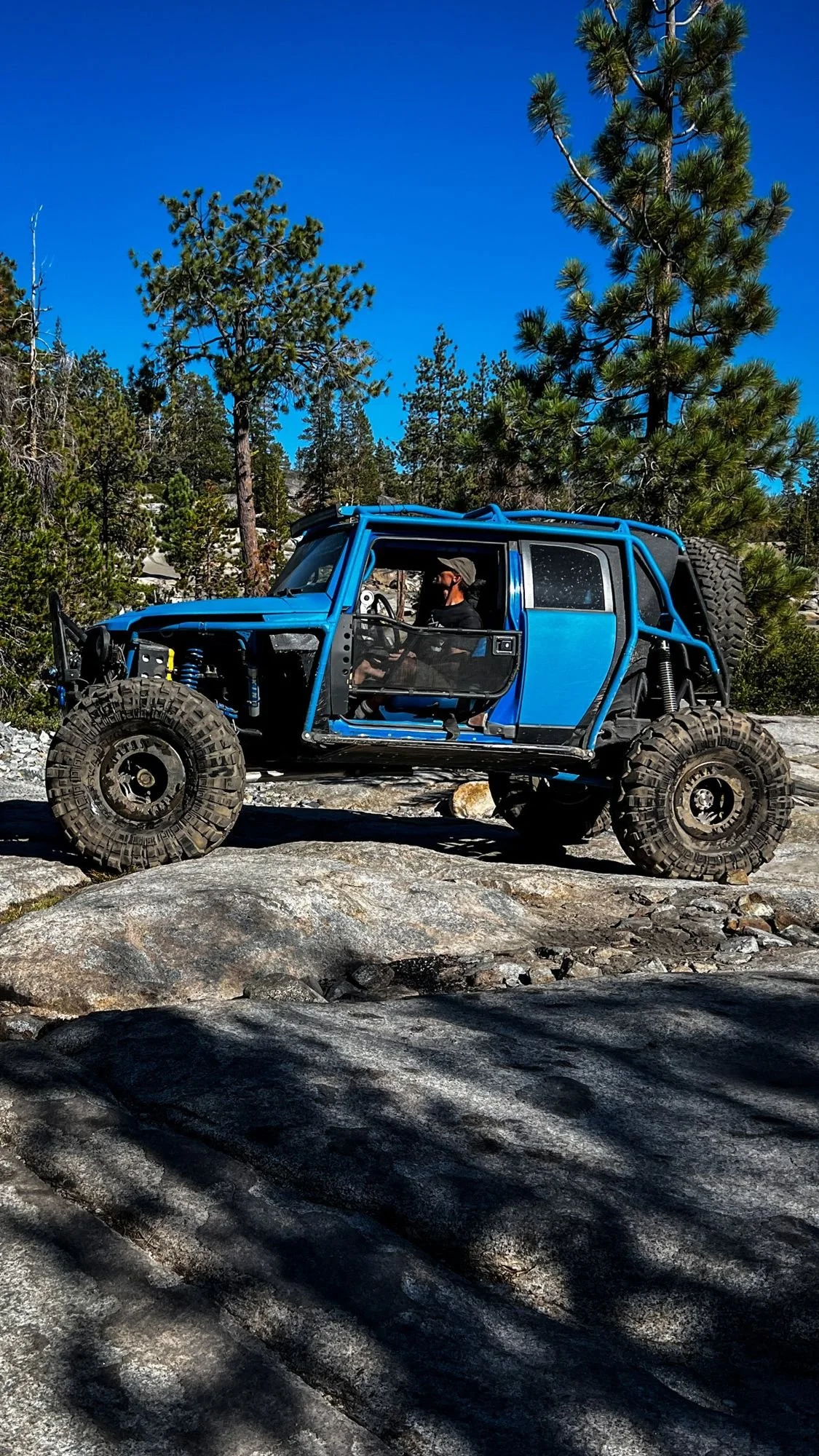 Blue Jeep with no doors on a tilted granite slab on the Rubicon Trail in California during Rubithon 2022