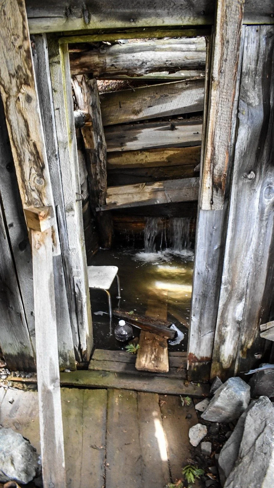 Old timber-lined mine shaft entrance with weathered boards in the Elkhorn Mountains near Boulder, Montana
