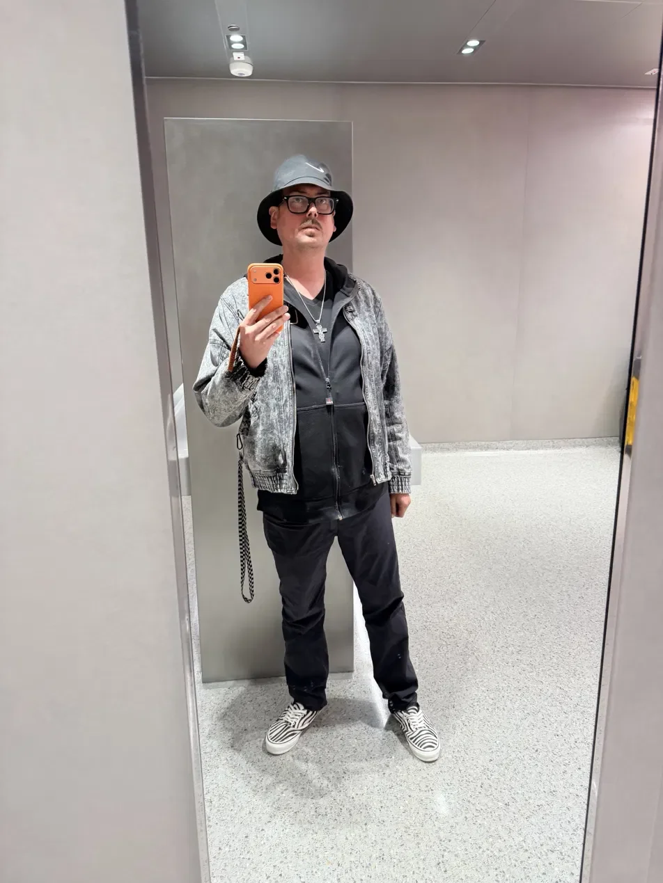 Aaron's mirror selfie on the day of his clear scan results, wearing a bucket hat and a cross necklace