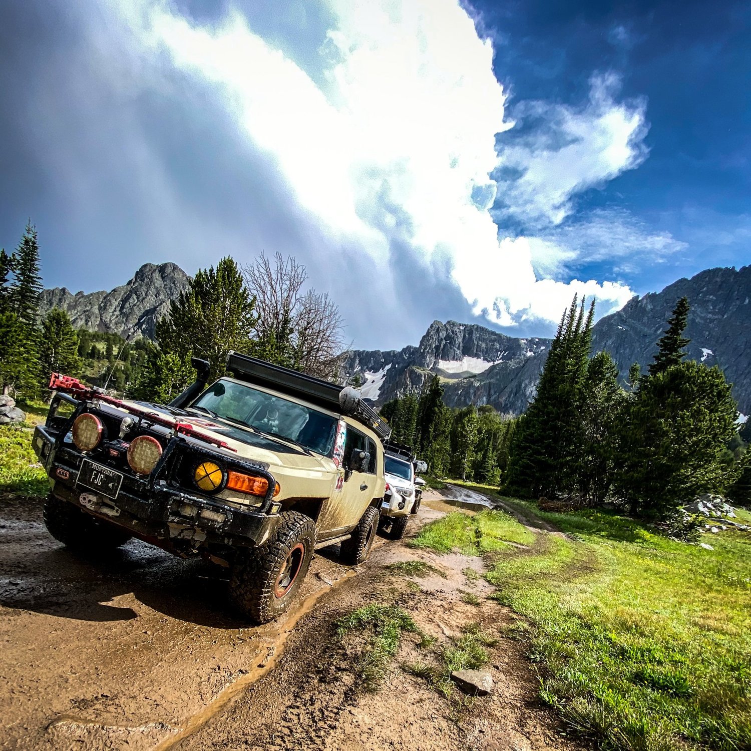 Tan Toyota FJ Cruiser climbing a dirt two-track below rocky peaks on the Blue Lake route