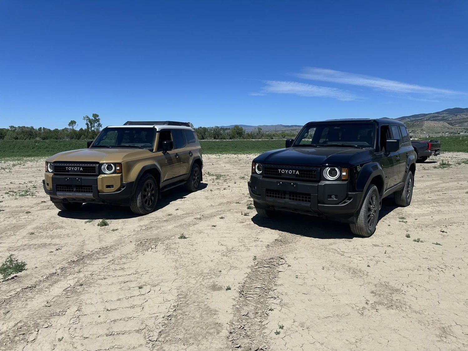 Tan and black 2024 Toyota Land Cruiser 250s parked side by side on a dirt course at XOverland Ranch near Bozeman, Montana