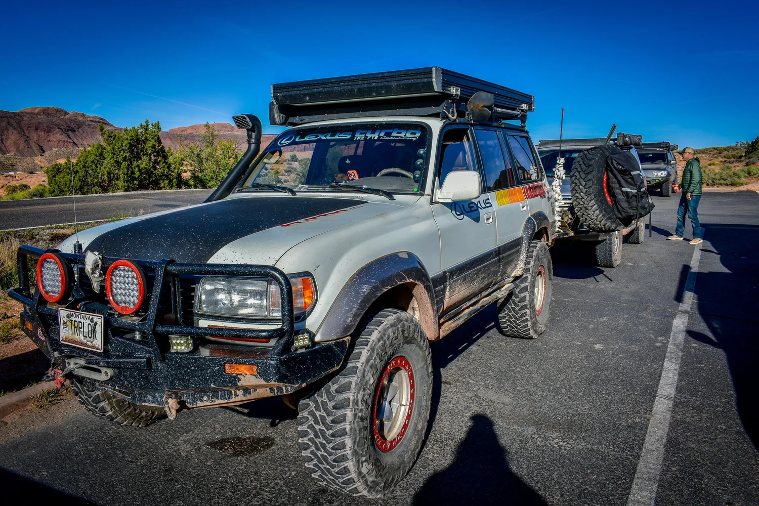 Silver Lexus LX450 with a rooftop tent, steel bumper and big tires parked on a road at Cruise Moab