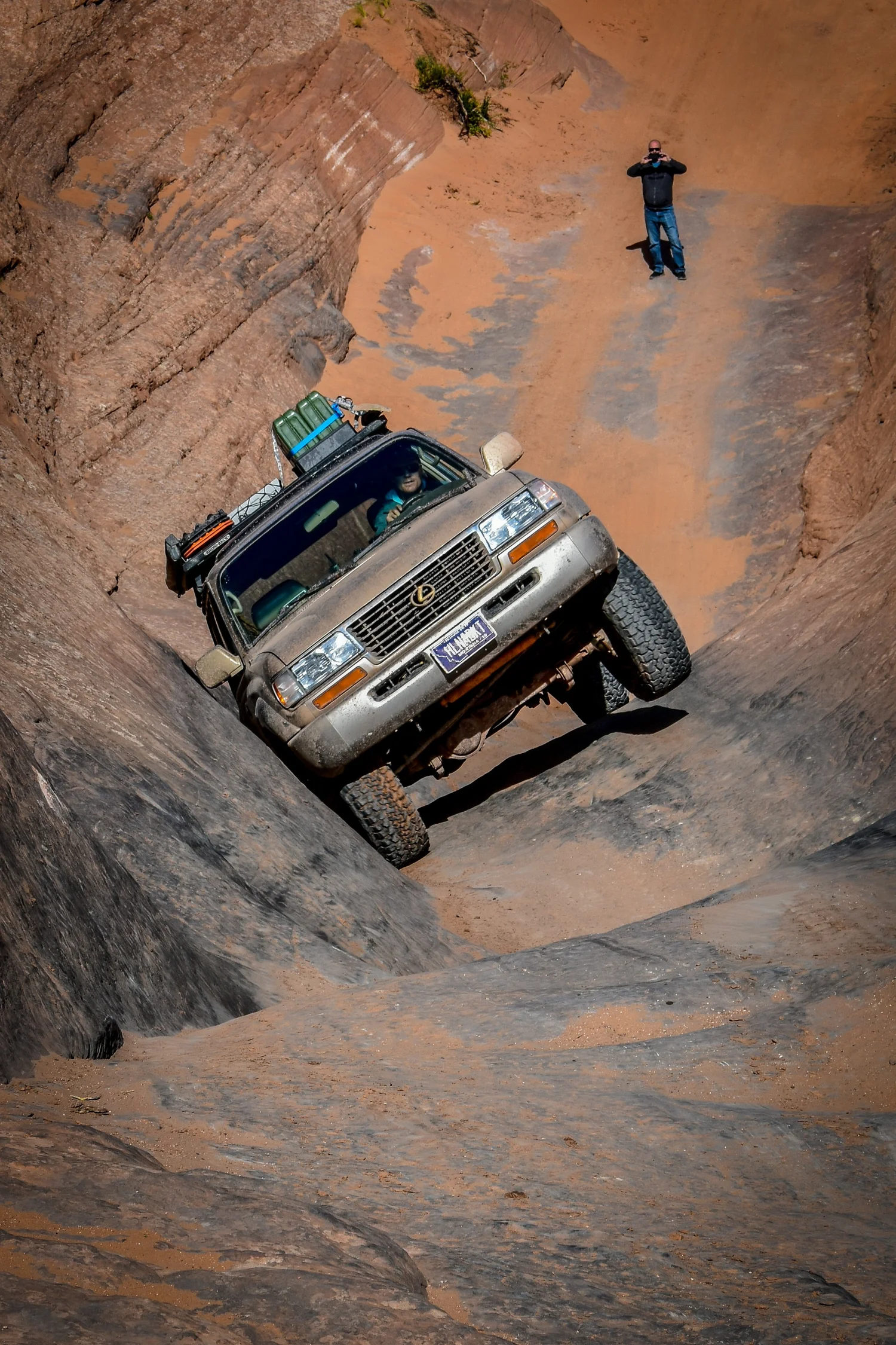 Silver Lexus LX450 climbing a steep slickrock chute at Cruise Moab
