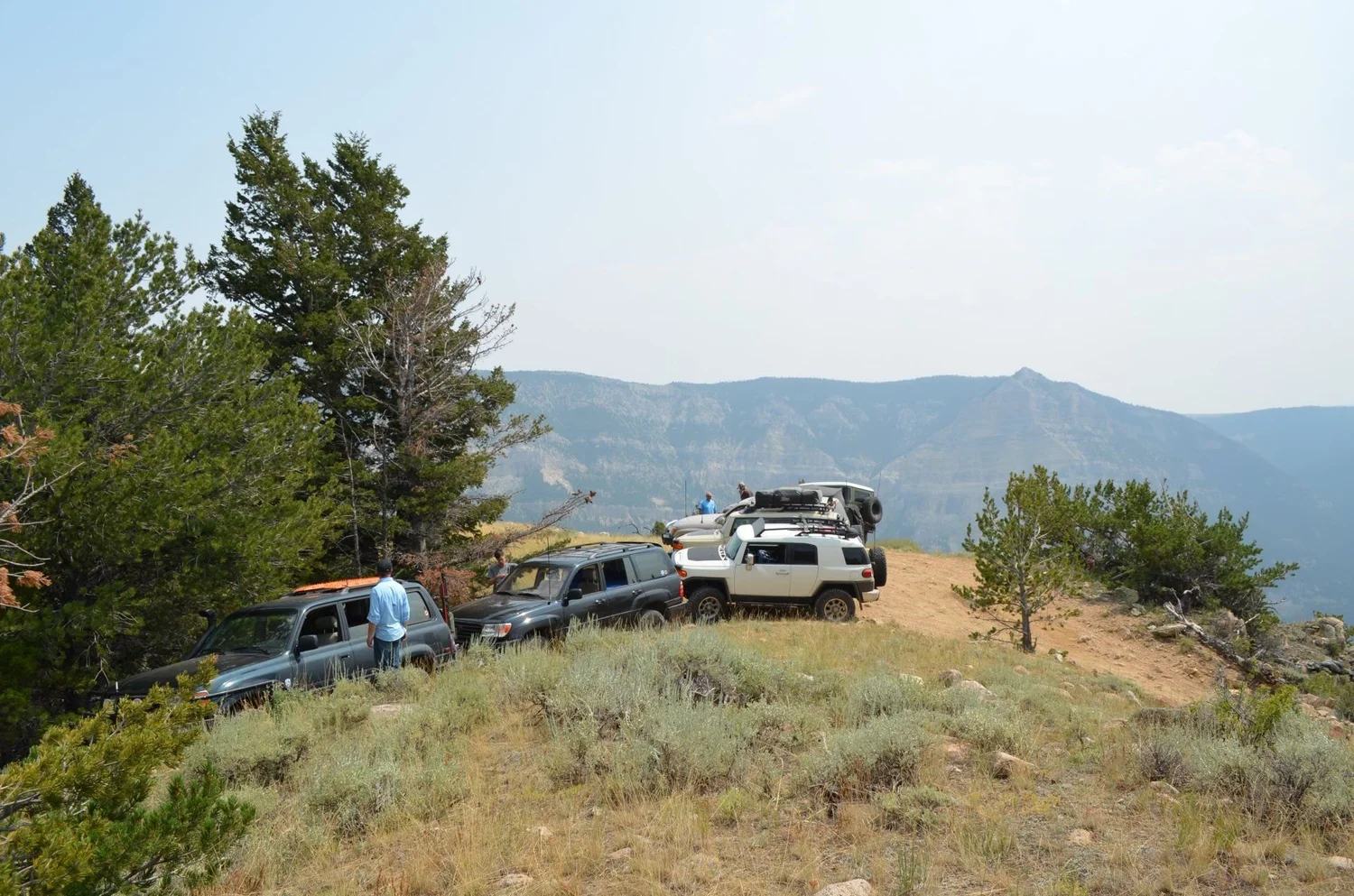 Trucks parked on a ridge with pines and a canyon rim behind on the Morrison Jeep Trail in Clarks Fork Canyon near Cody, Wyoming