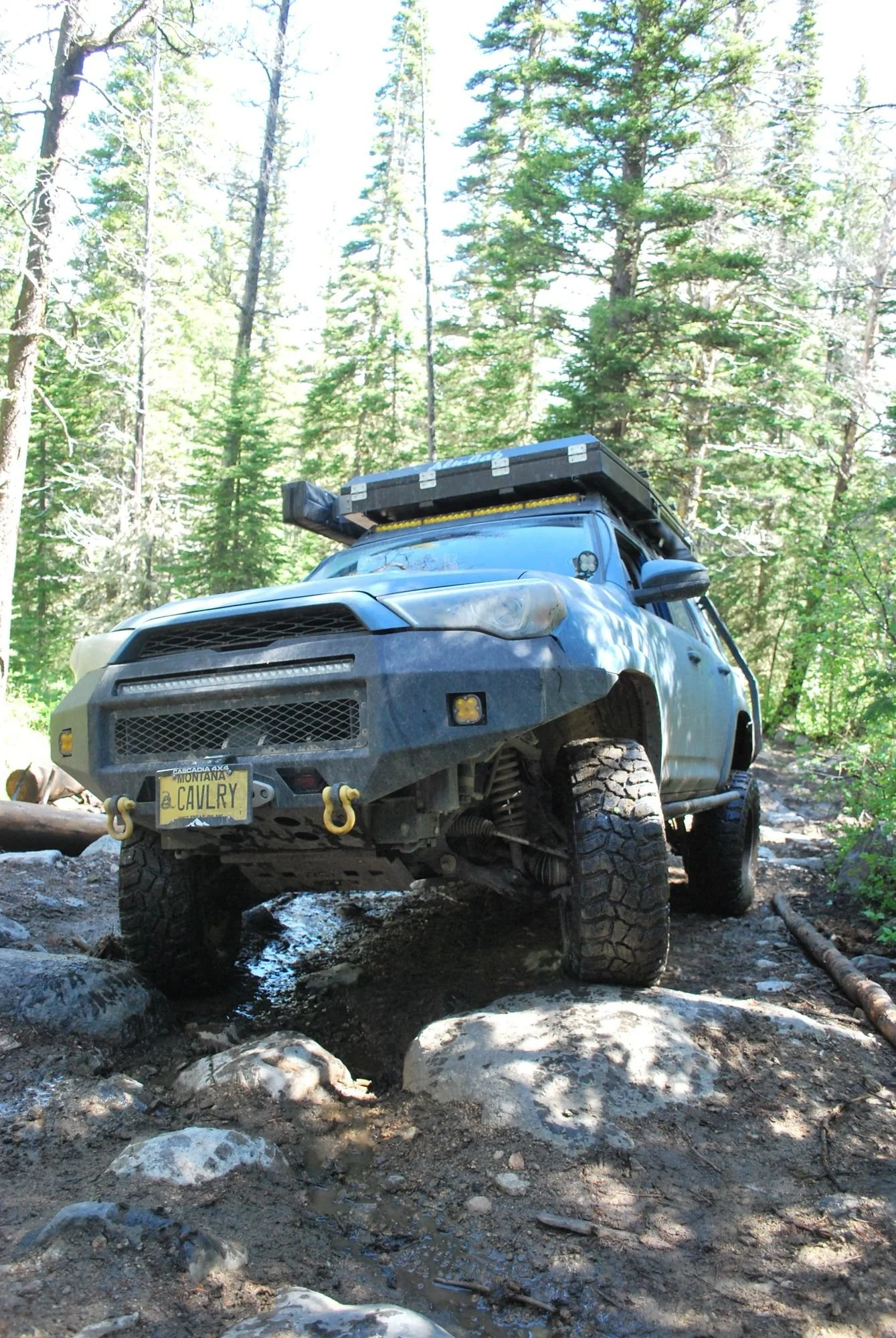 Blue 4Runner flexing one front wheel high over a boulder on the North Meadow Creek Twin Lakes trail in the Tobacco Root Mountains, Montana
