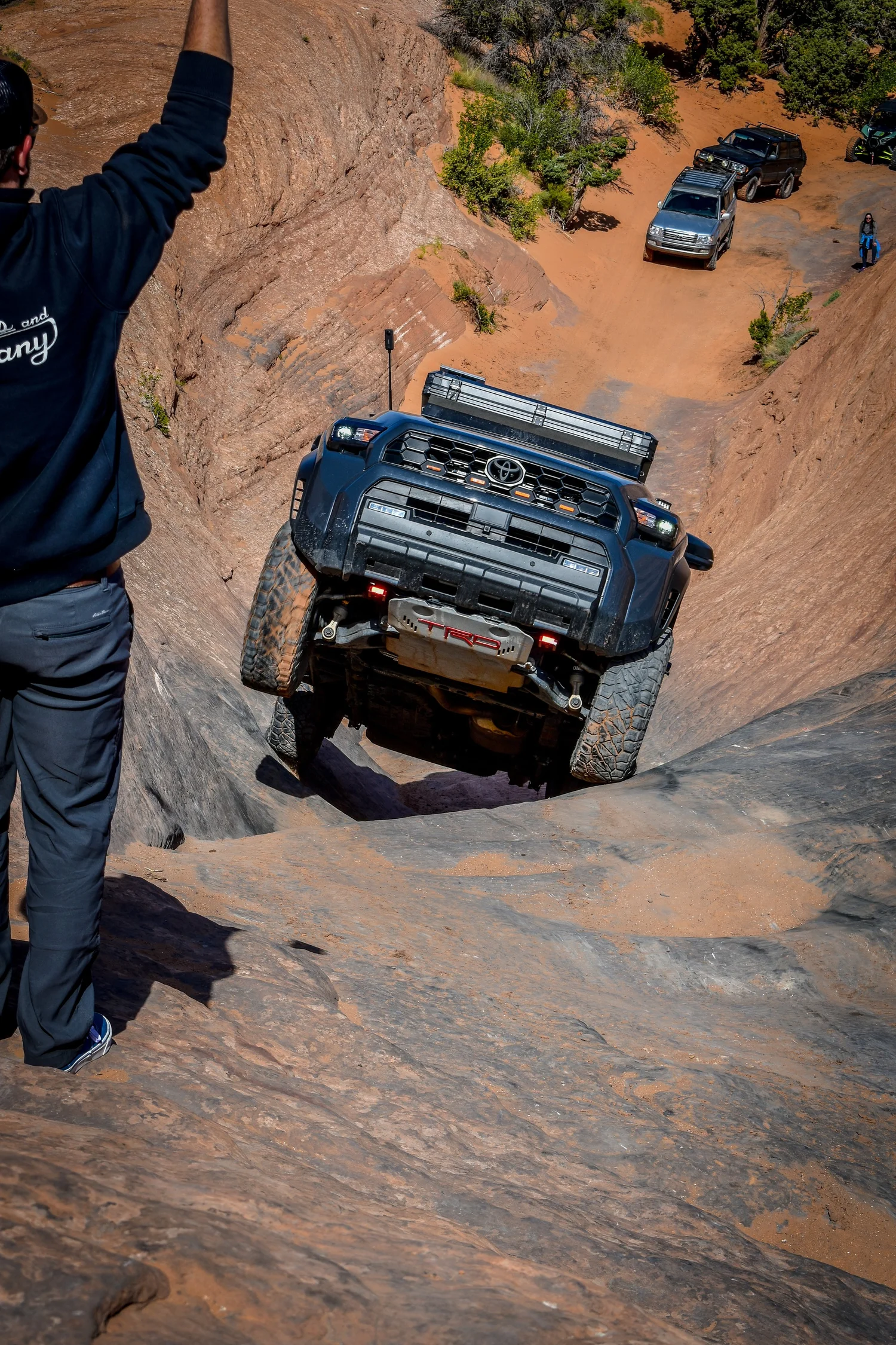 Black Toyota Land Cruiser crawling down a steep slickrock chute at Cruise Moab