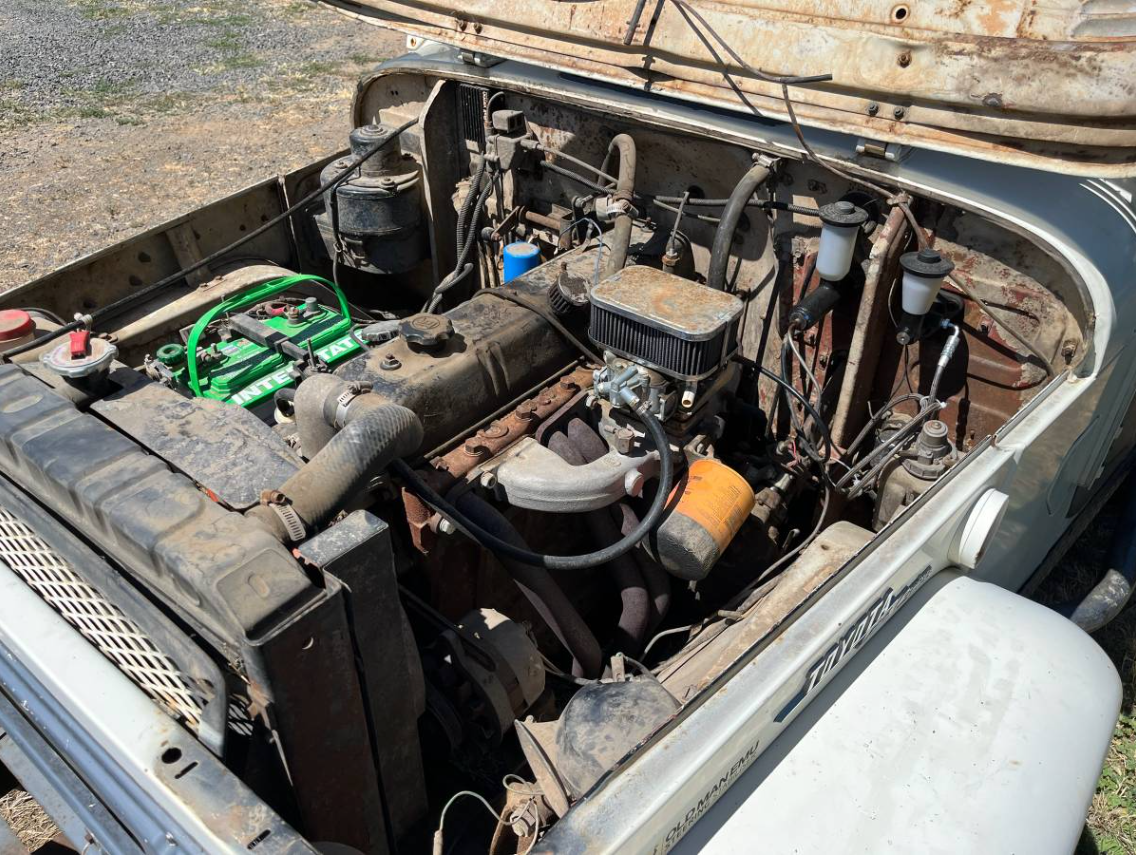 Engine bay of the 1969 Toyota FJ40 showing the inline-six and a fresh battery