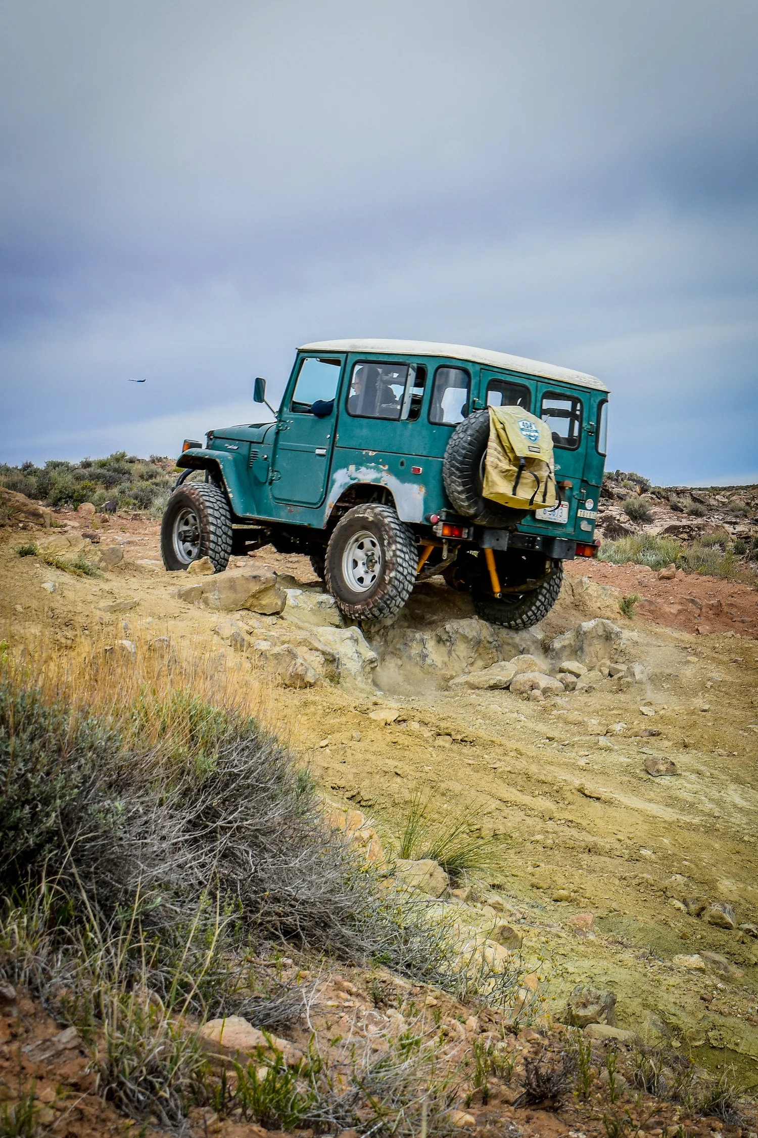Teal Toyota FJ40 Land Cruiser climbing a rocky slope on the 3D Trail at Cruise Moab
