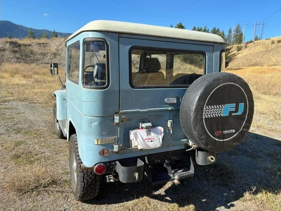 Rear quarter view of the light blue 1967 FJ40 with spare tire cover and receiver hitch