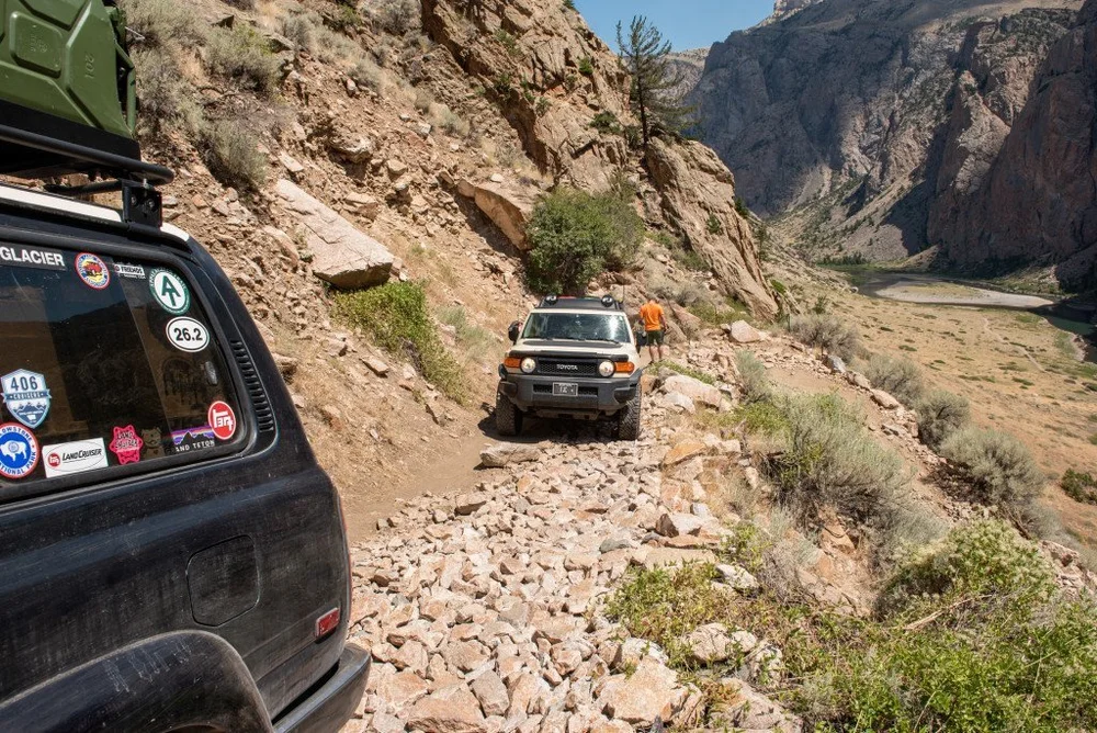 4x4 descending a rocky shelf road with the canyon behind