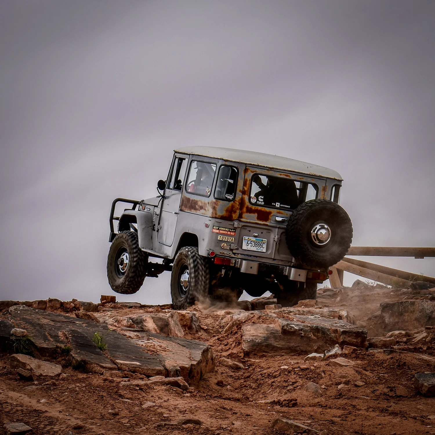 Gray Toyota FJ40 Land Cruiser at the top of a rock ledge on the 3D Trail at Cruise Moab