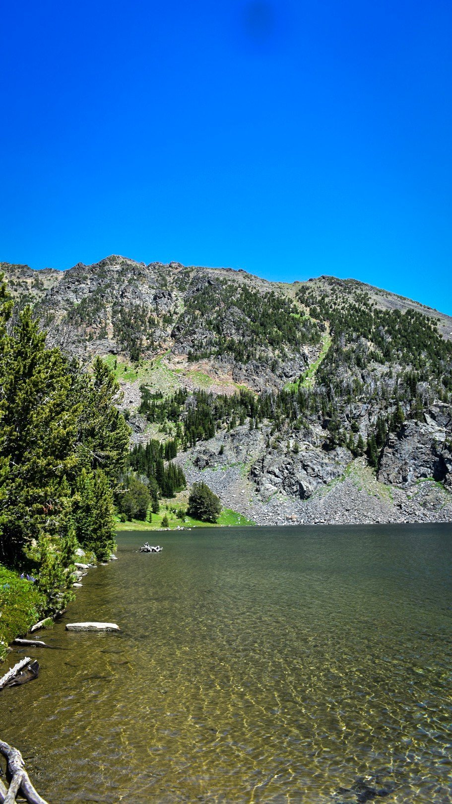 Clear shallow water at the lake edge below rocky slopes