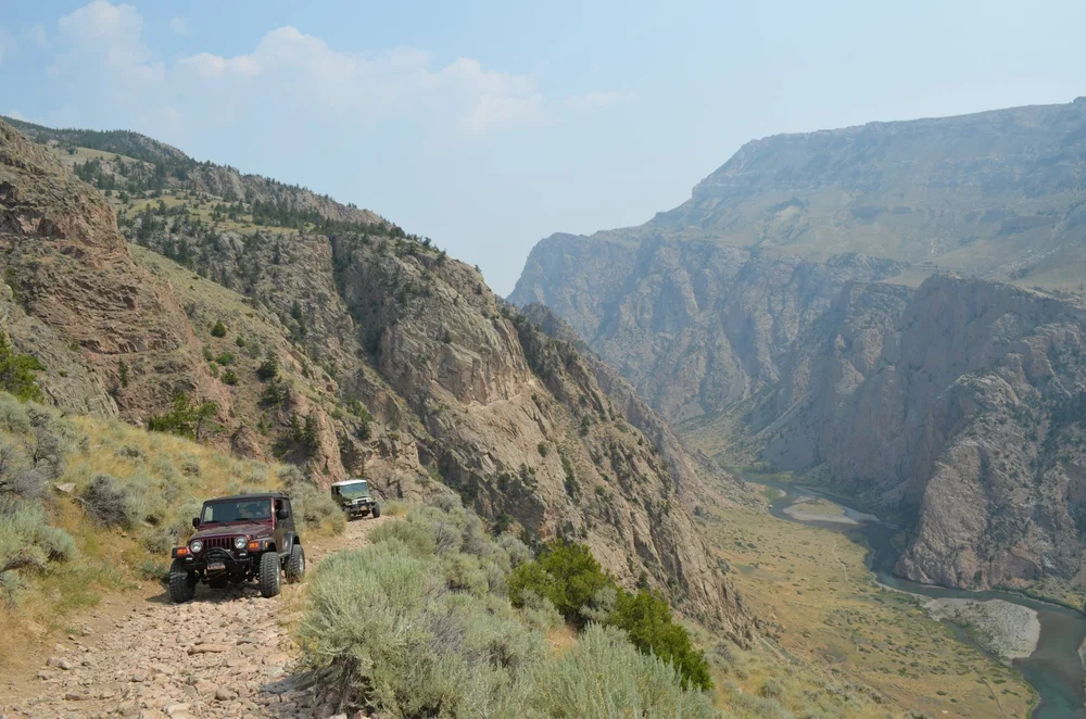 Two 4x4s on the trail with the deep canyon below