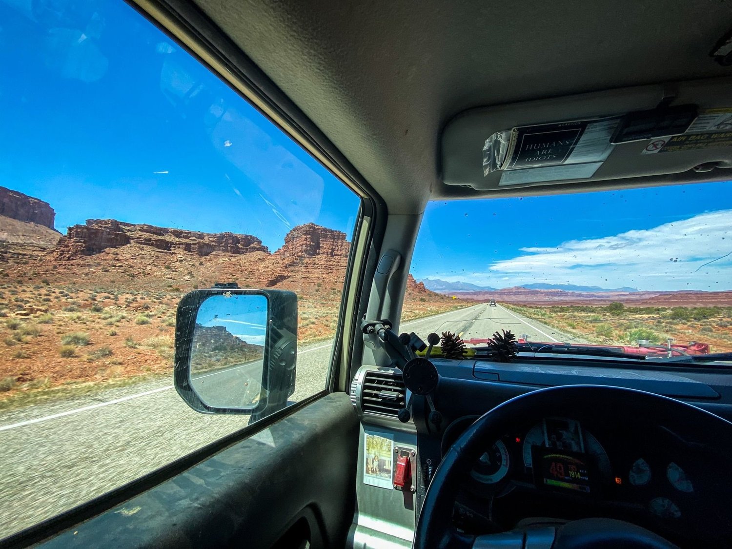 View through an FJ Cruiser window of red cliffs and mesas beside a highway on a spring road trip through Utah