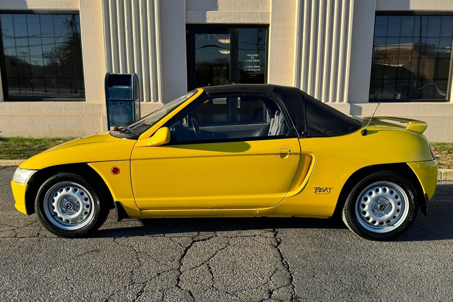 Side view of the yellow 1991 Honda Beat with the soft top up