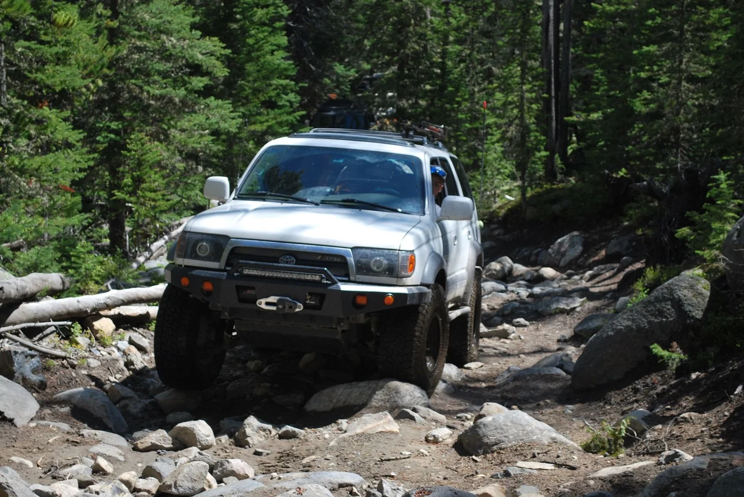 White third-generation 4Runner crawling down a rocky section with logs on the trail on the North Meadow Creek Twin Lakes trail in the Tobacco Root Mountains, Montana