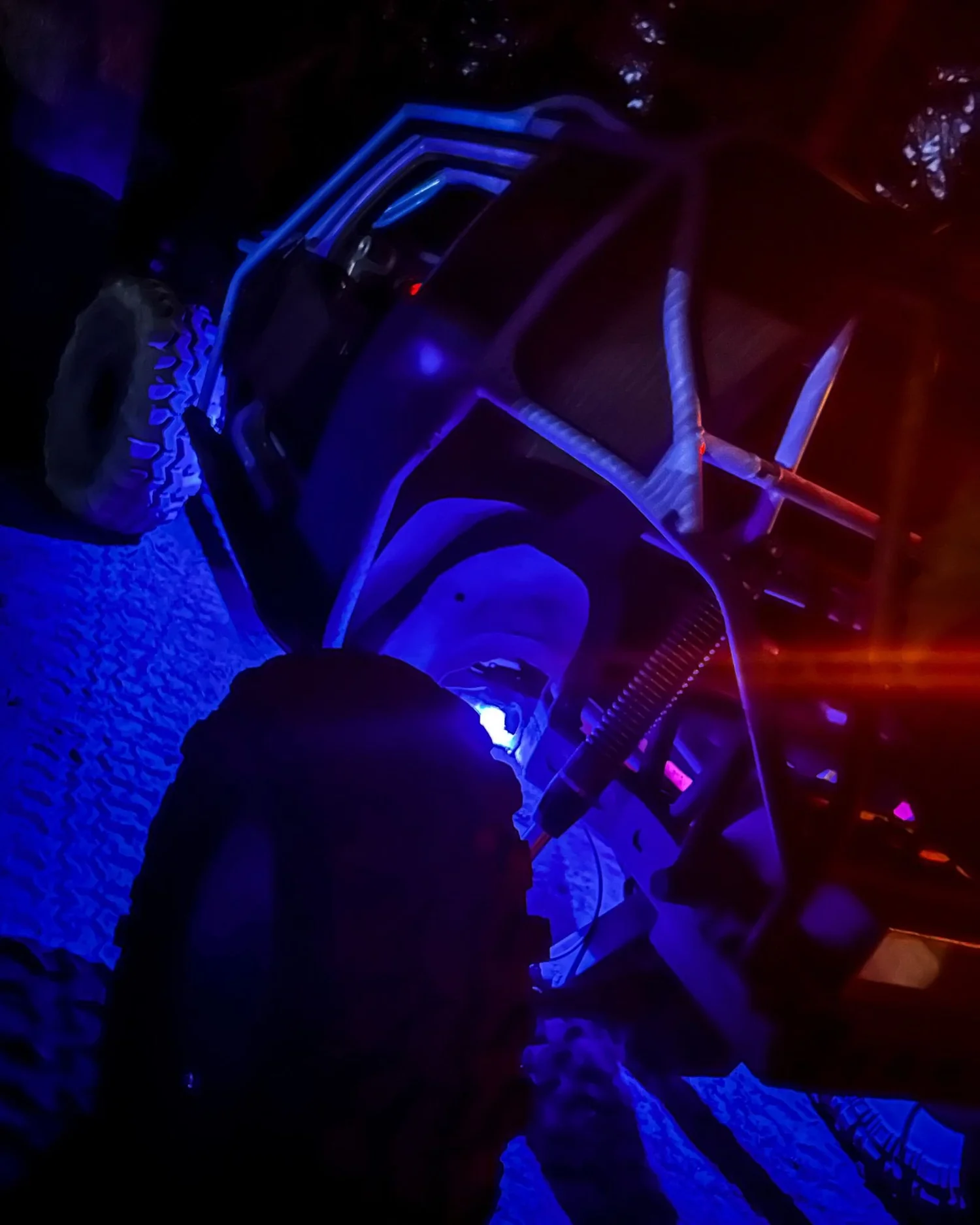 Close view of a rig&rsquo;s suspension lit purple and blue at night on the Rubicon Trail in California during Rubithon 2022