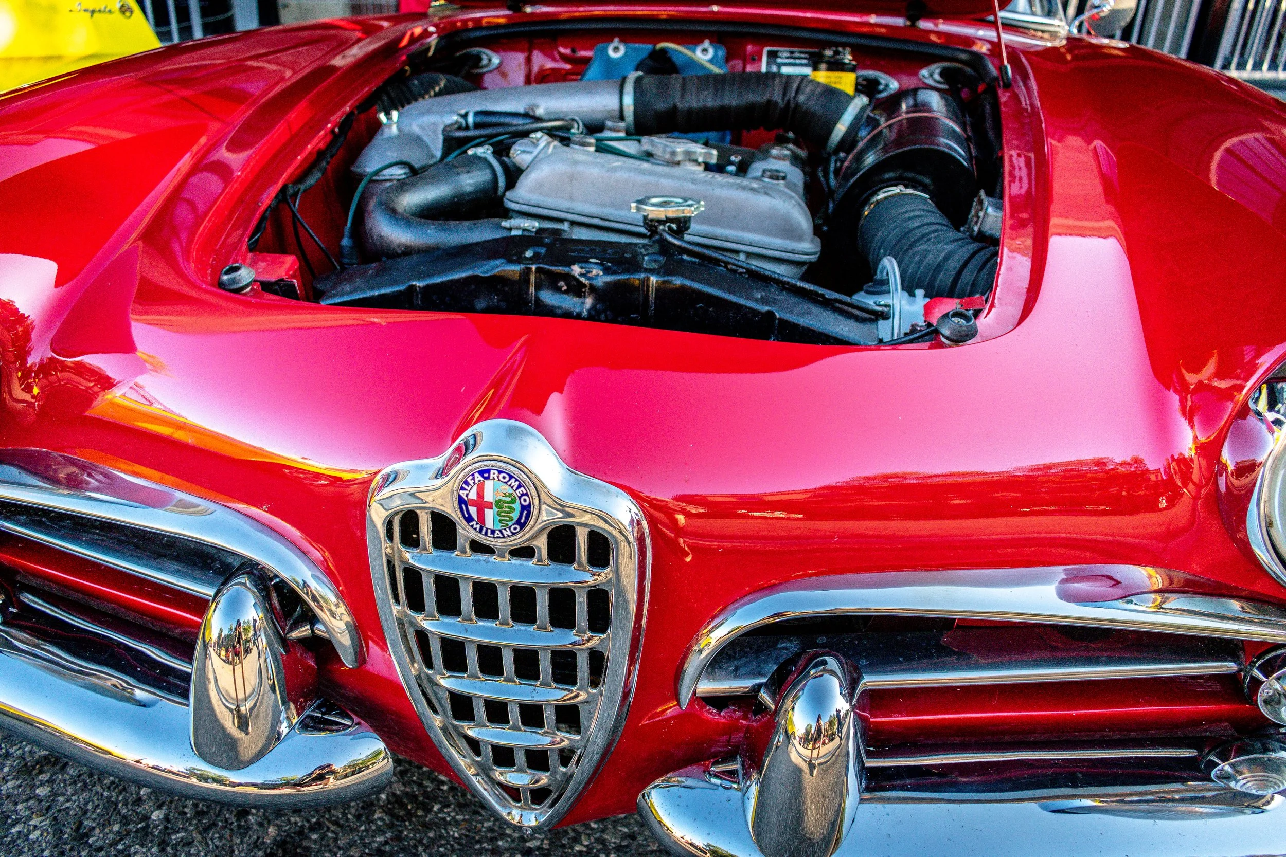 Close-up of the Alfa Romeo grille shield badge with the engine bay visible above
