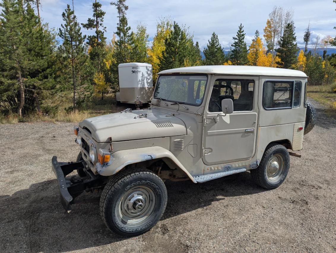 Beige 1977 Toyota FJ40 hardtop parked among aspens and pines in Fraser, Colorado