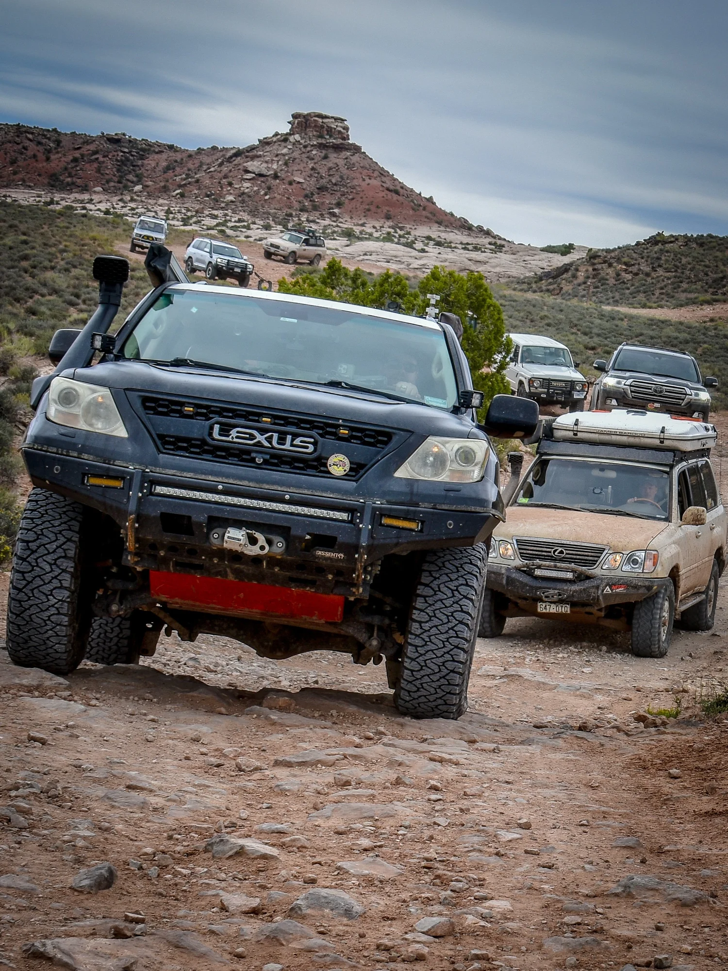 Black Lexus LX470 with a snorkel and steel bumper leading a line of trucks on the 3D Trail at Cruise Moab