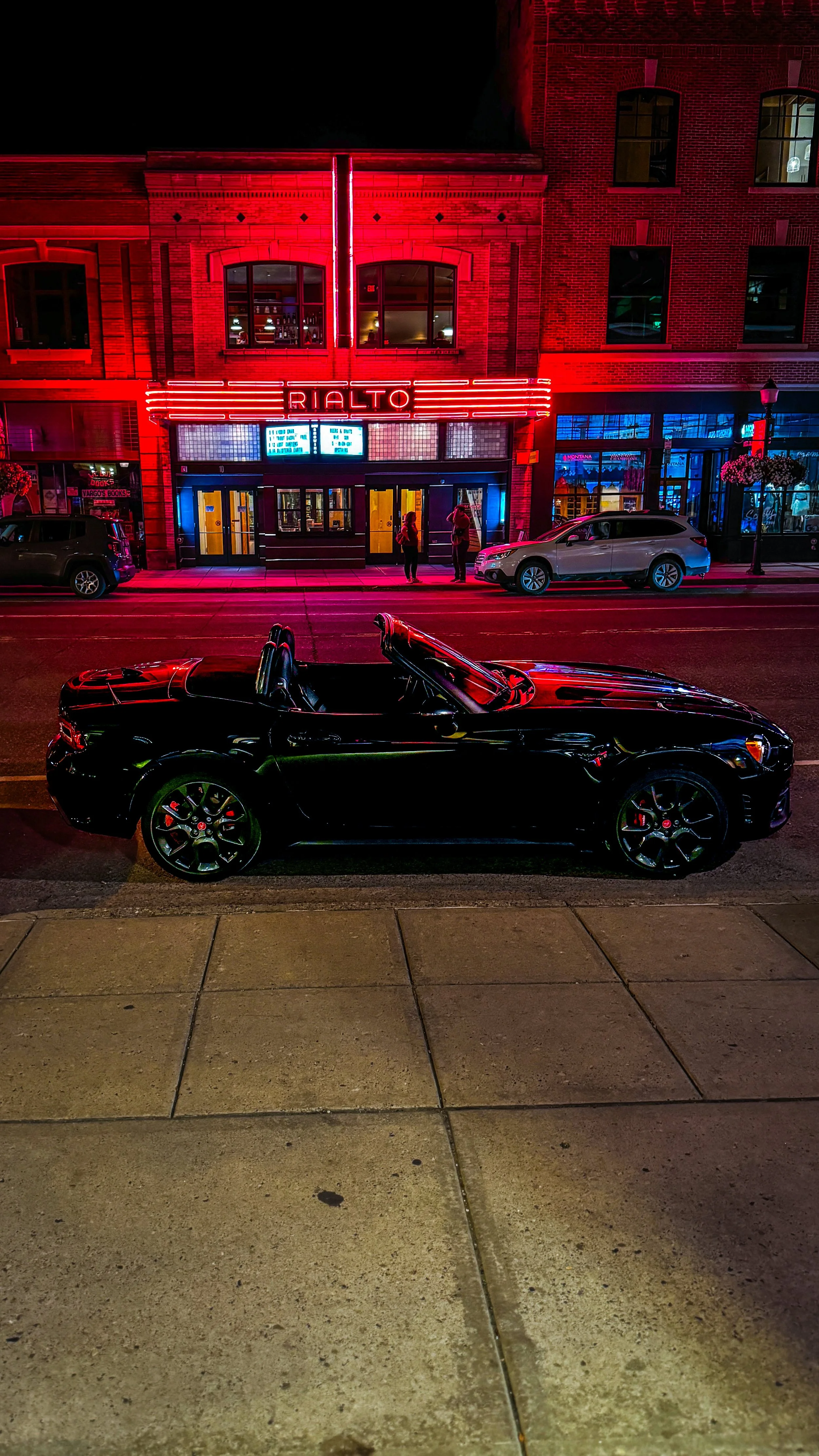 Black Fiat 124 Spider Abarth outside the Rialto Theatre in Bozeman at night