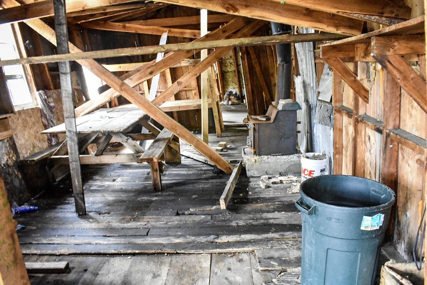 Interior of an old mining cabin with wooden framing, a stove and a picnic table in the Elkhorn Mountains near Boulder, Montana