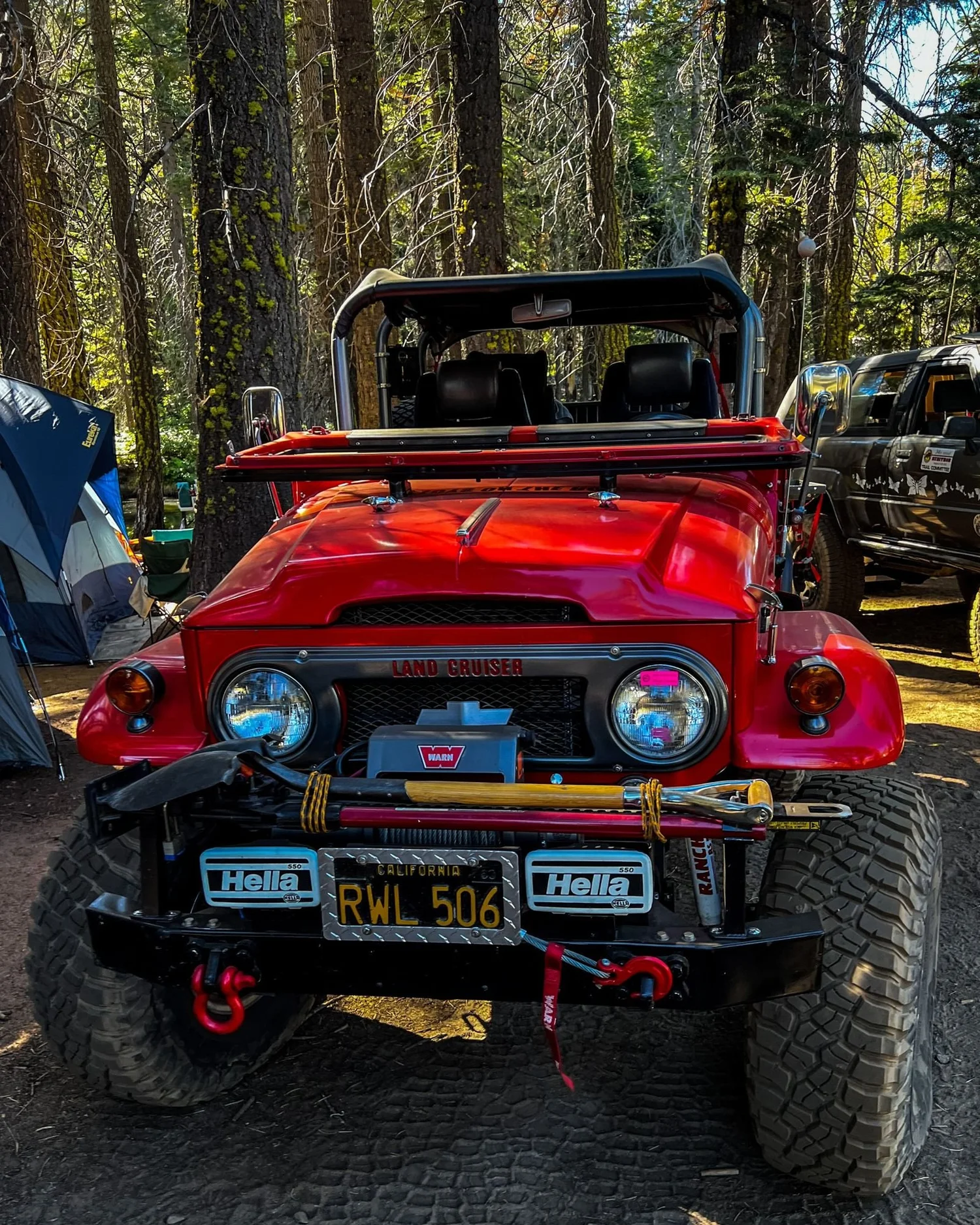 Red Toyota FJ40 with a winch and Hella lights parked in camp on the Rubicon Trail in California during Rubithon 2022