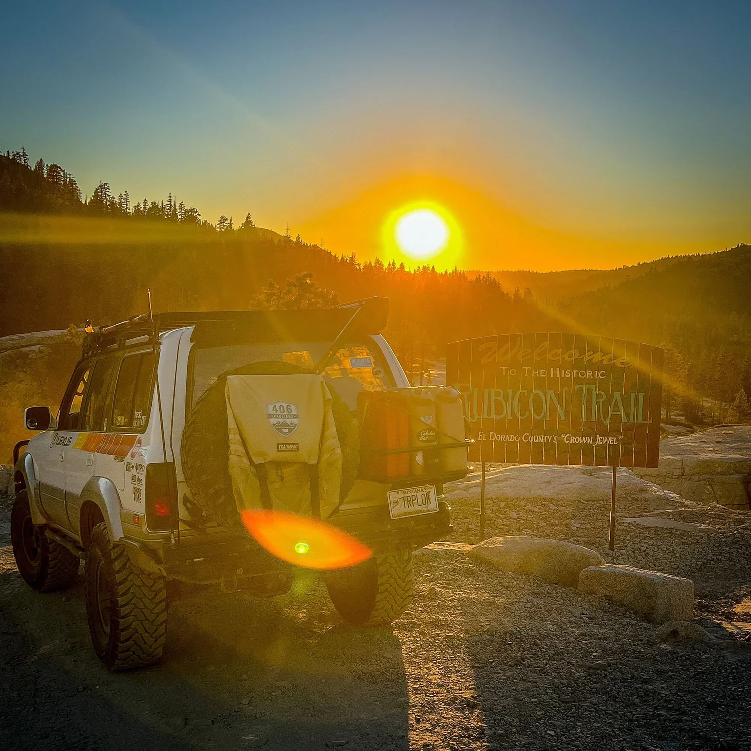 Lexus LX450 parked beside the Rubicon Trail welcome sign with the sun rising over the ridge on the Rubicon Trail in California during Rubithon 2022