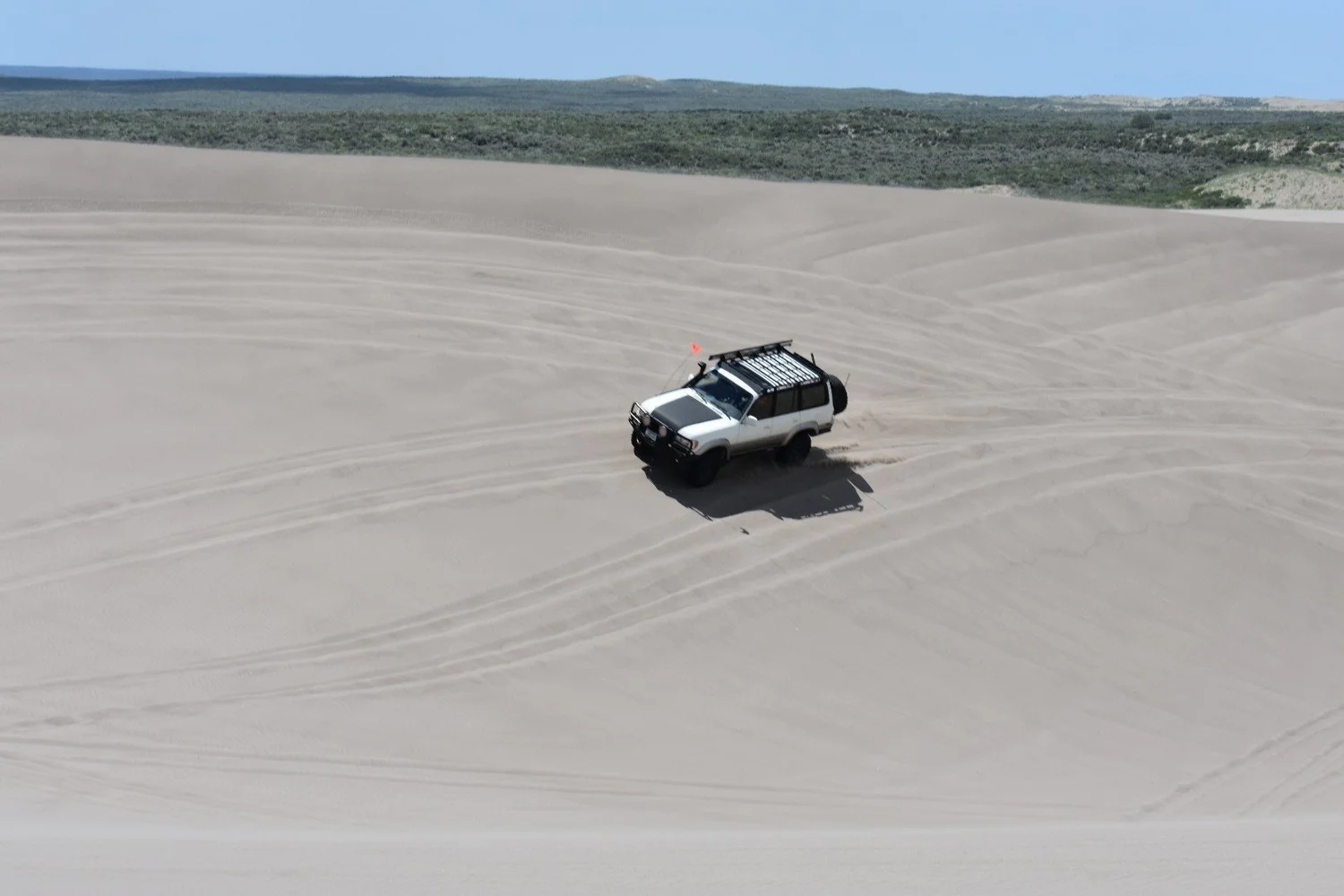 White 80 Series Land Cruiser with a full roof rack crossing rippled sand at the St. Anthony Sand Dunes in Idaho