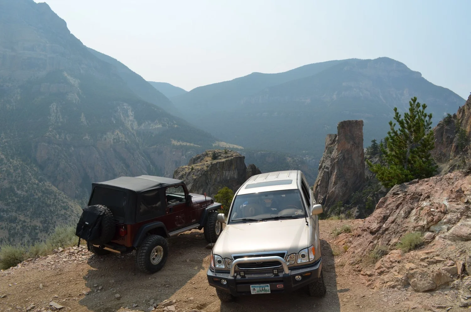 Maroon Jeep Wrangler and silver Tacoma parked at a rocky overlook above the canyon on the Morrison Jeep Trail in Clarks Fork Canyon near Cody, Wyoming