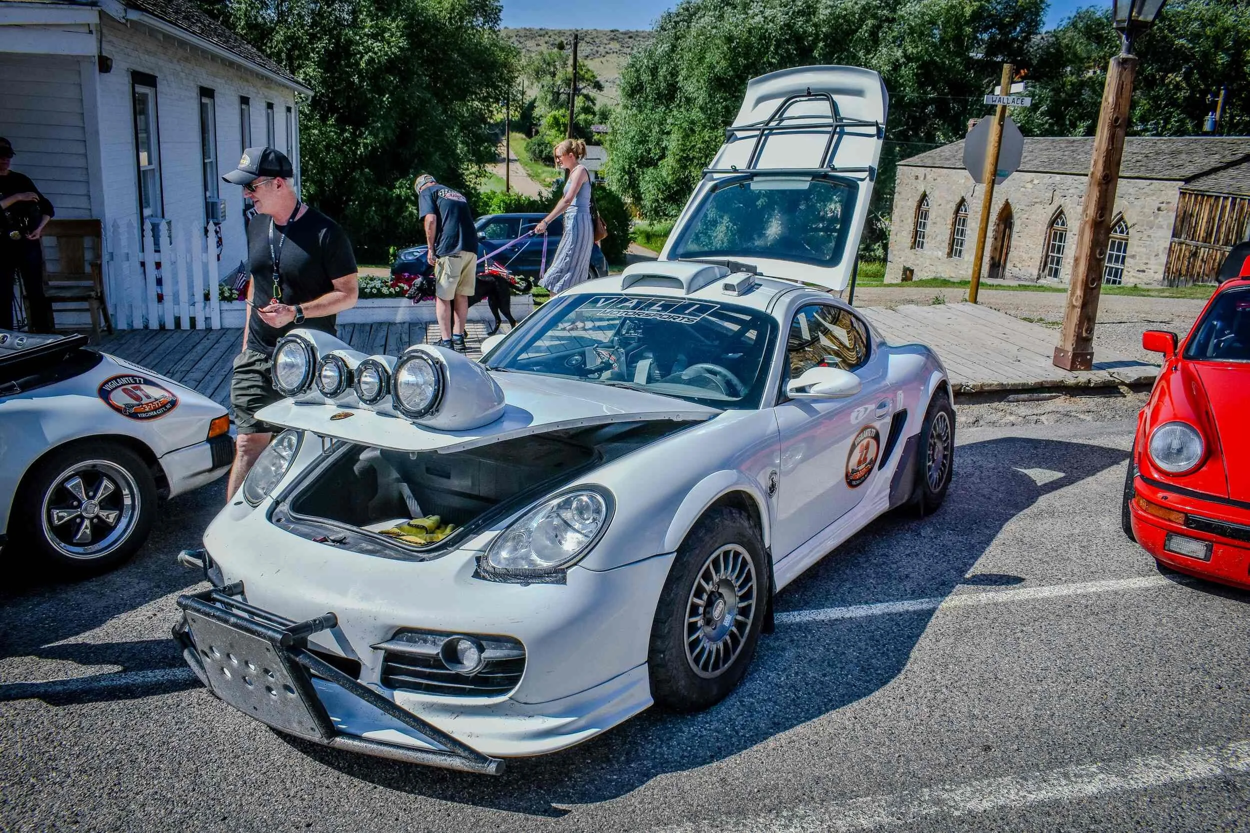 Silver dirt-prepared Porsche Cayman with rally lights and roof basket