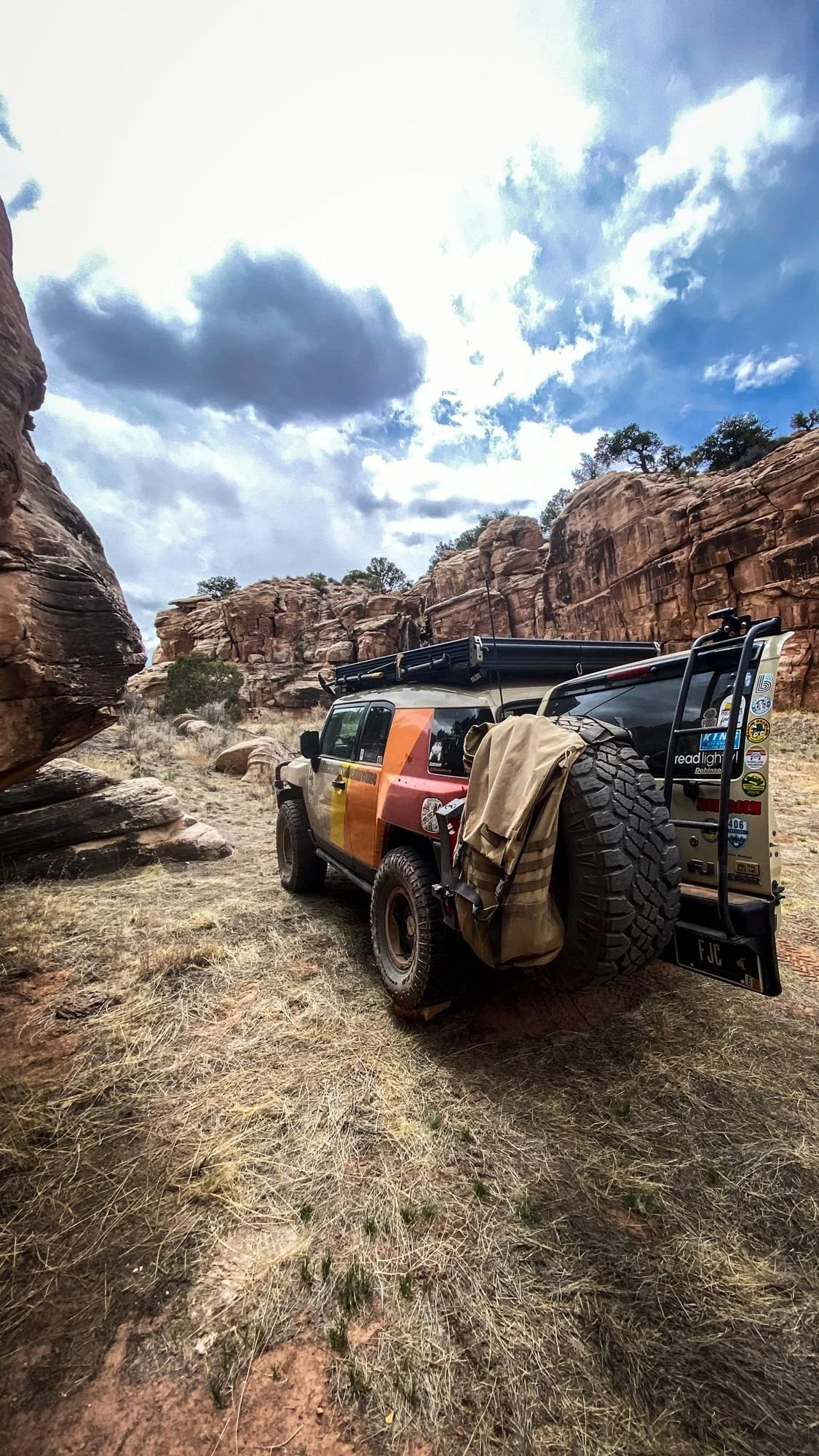 Striped FJ Cruiser parked in a narrow canyon below red rock walls on a spring road trip through Utah