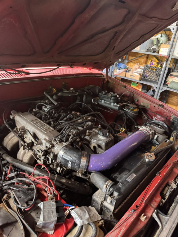 Engine bay of the red 1989 Toyota 4Runner with a purple intake tube