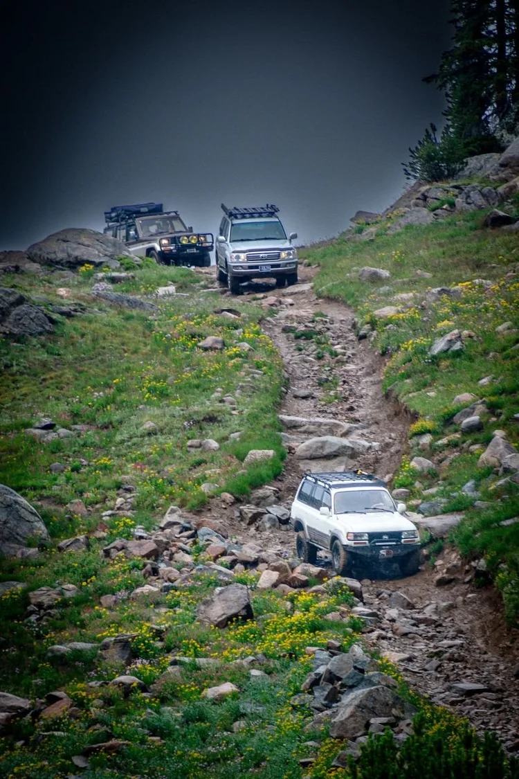 Land Cruisers climbing a loose, rocky two-track above treeline near Cooke City.