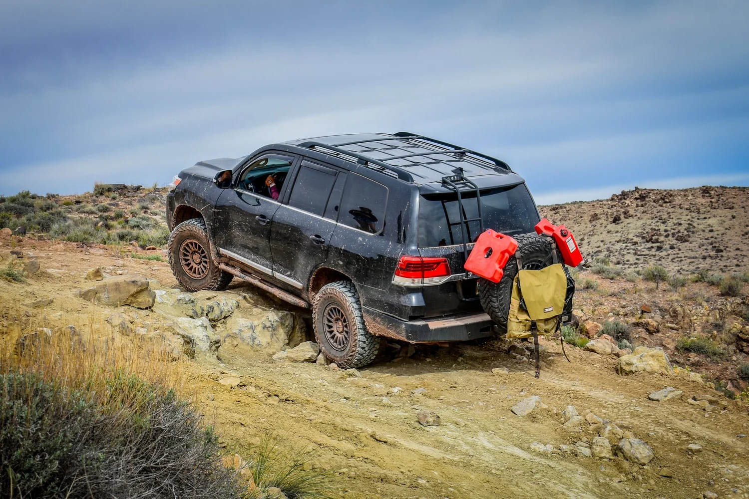Black 200 Series Toyota Land Cruiser with recovery gear on the rear climbing rocks on the 3D Trail at Cruise Moab
