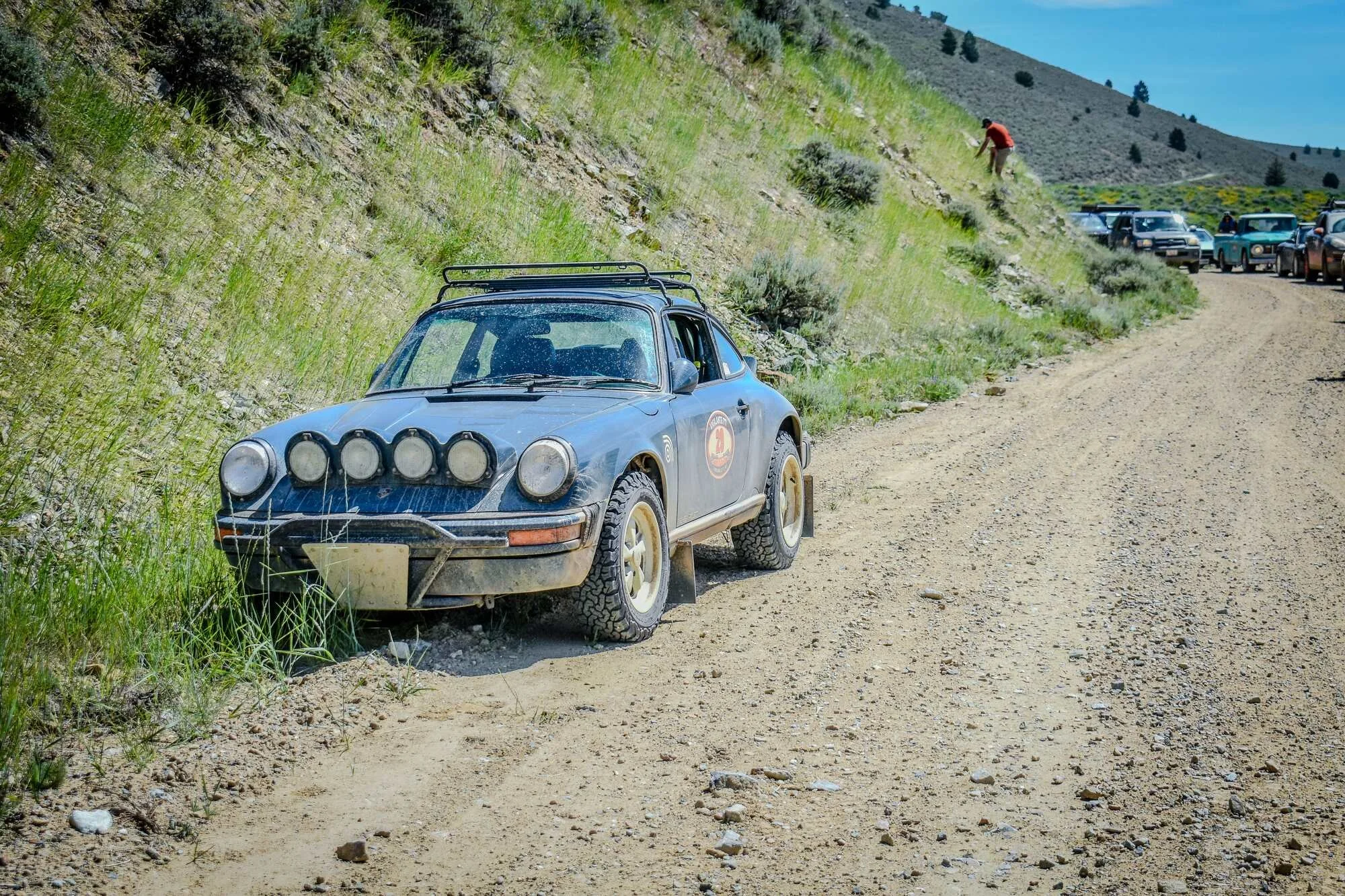 Auxiliary-light-equipped rally car driving through a Montana forest dirt stage