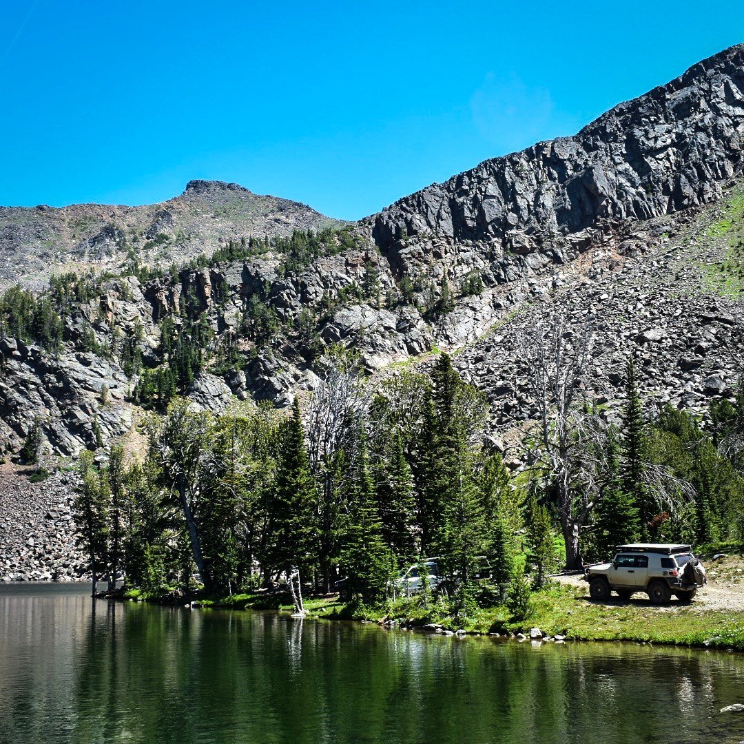 Toyota FJ Cruiser parked on the shore of Noble Lake below rocky cliffs, August 2019