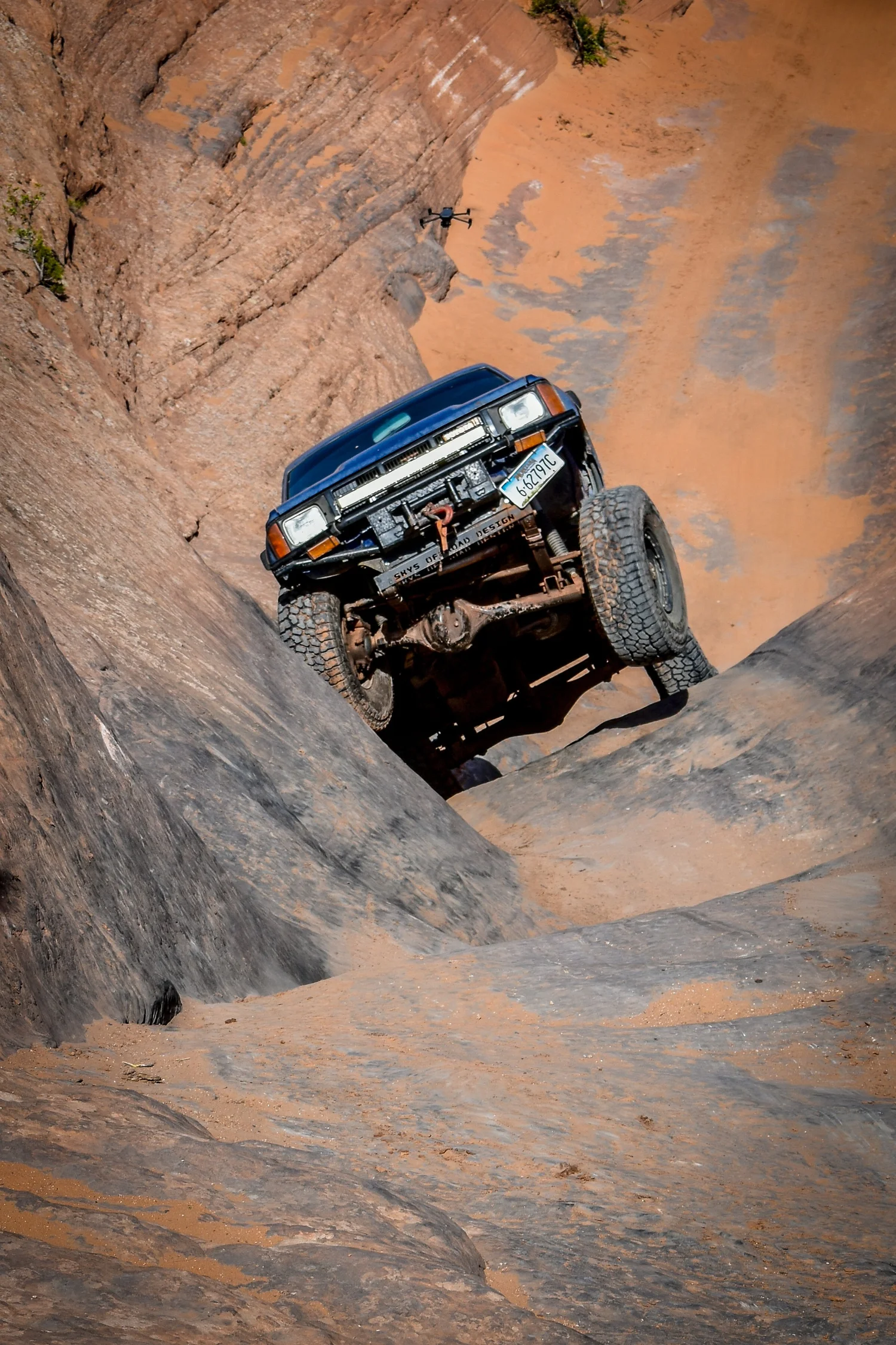 Toyota 4Runner crawling down a steep slickrock chute at Cruise Moab