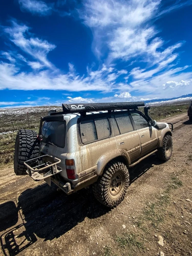 An 80 Series Land Cruiser on a muddy, rutted two-track under open sky on the Dillon club run.