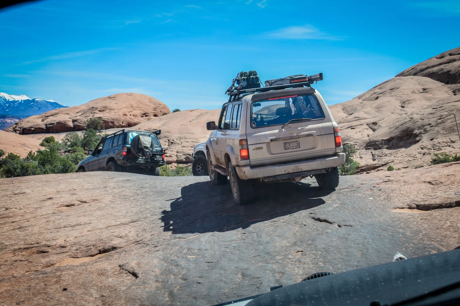 Silver Lexus LX450 with a roof rack on slickrock at Cruise Moab
