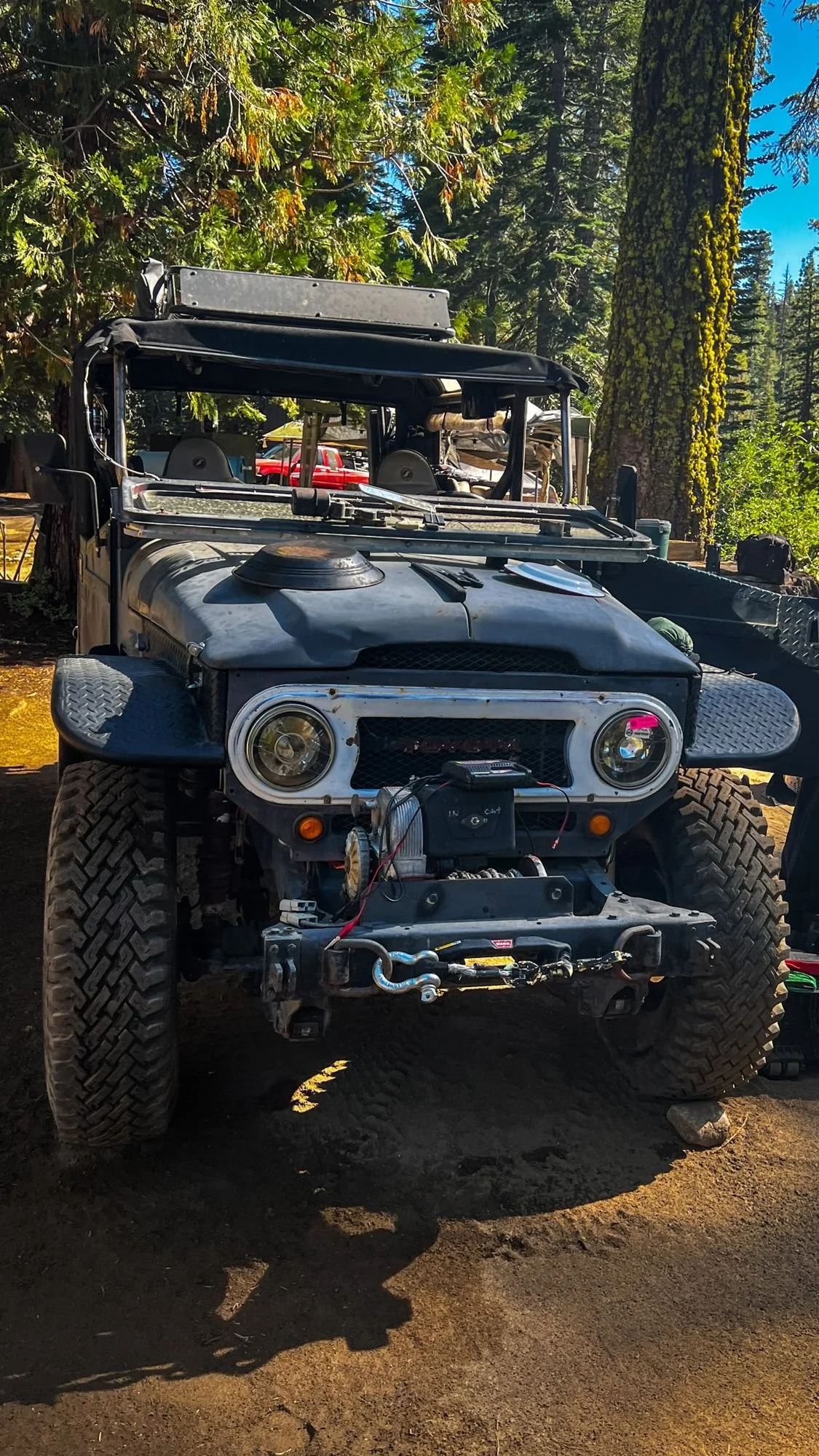 Gray Toyota FJ40 with a front winch parked among pines on the Rubicon Trail in California during Rubithon 2022