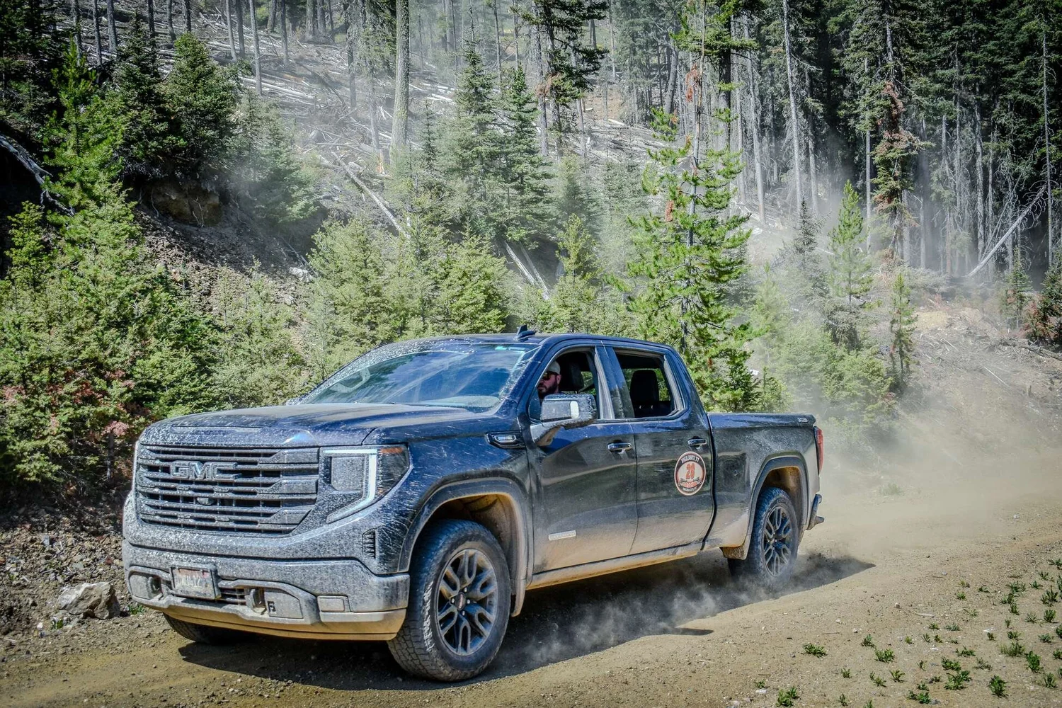 Toyota pickup kicking up dirt on a forest rally road