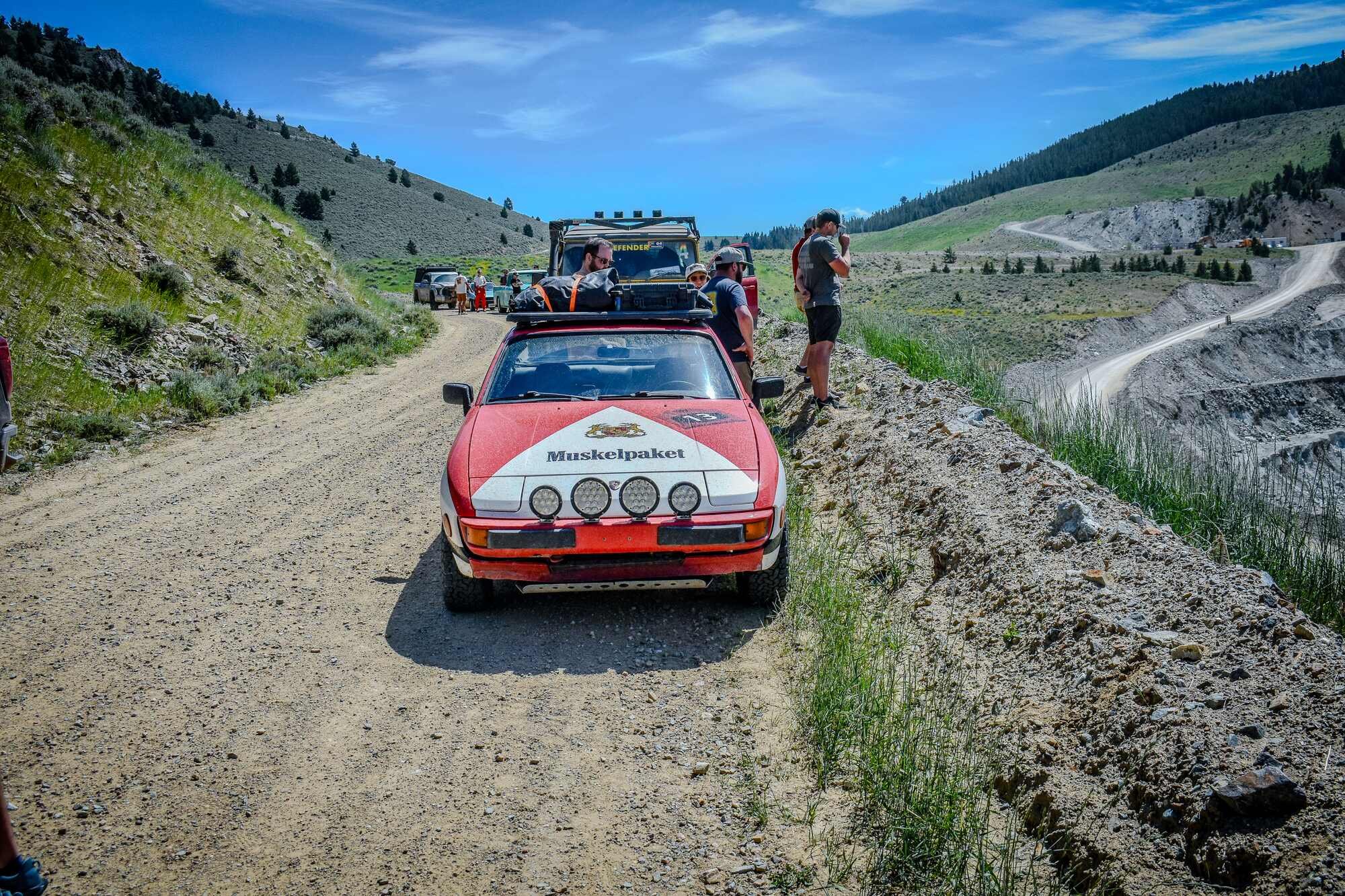 Red rally-prepared Porsche 944 stopped on a Montana dirt road during the Vigilante 77 Rally