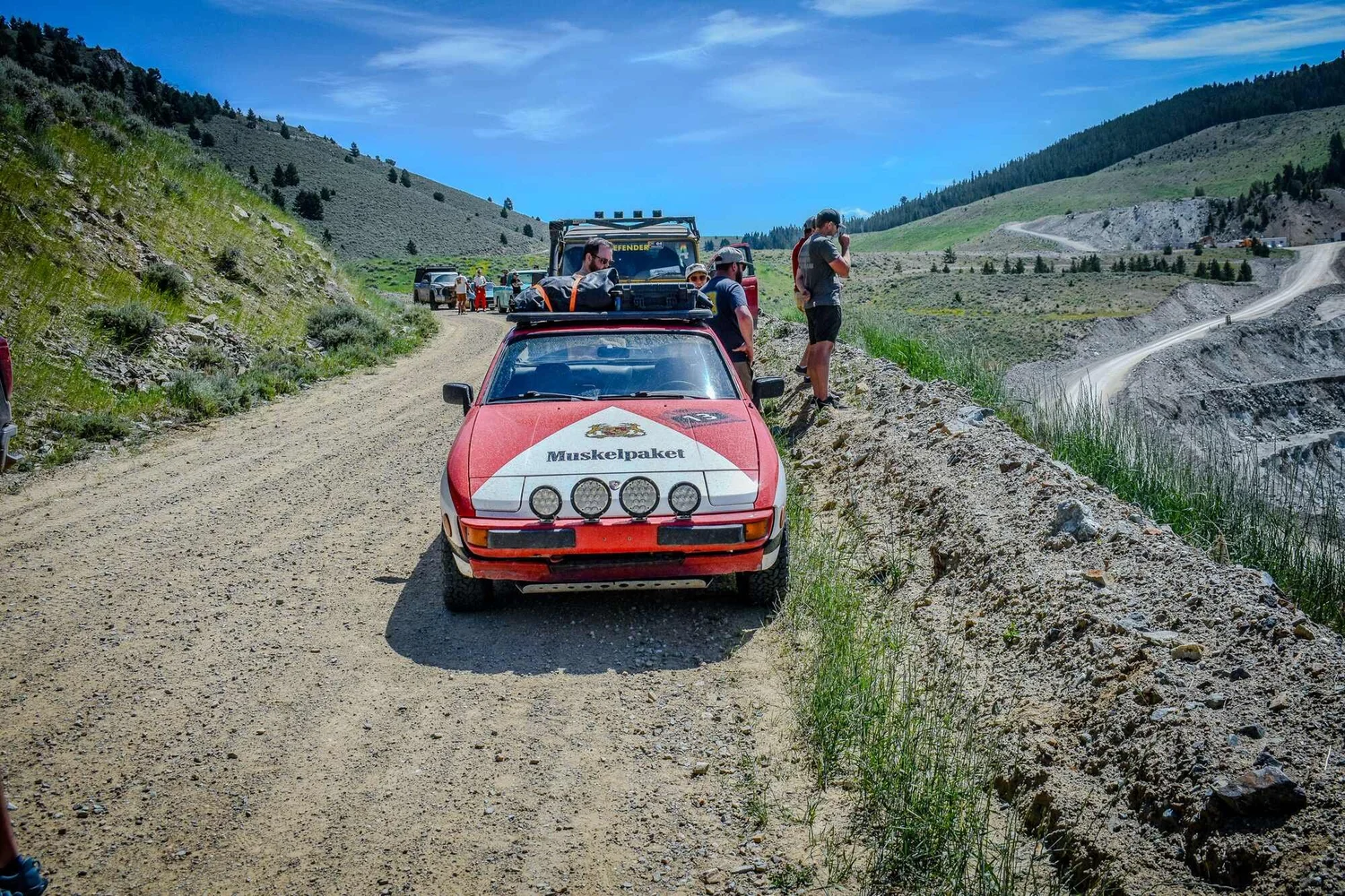 Red rally-prepared Porsche 944 stopped on a Montana dirt road during the Vigilante 77 Rally