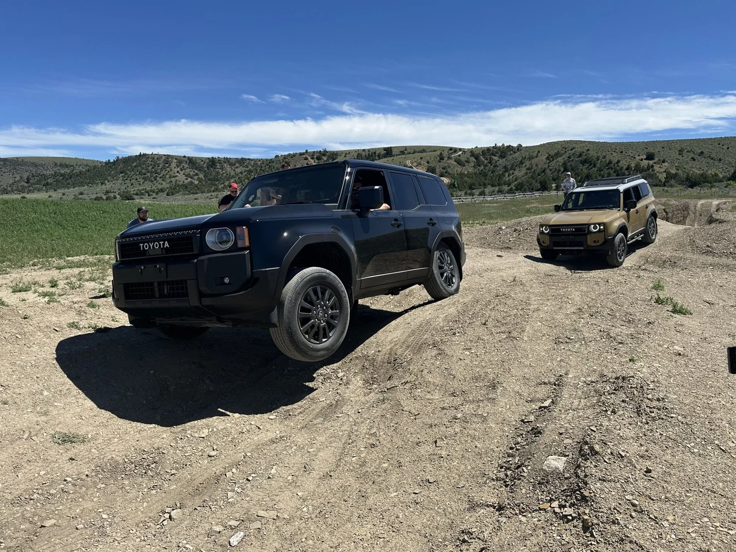 Black Land Cruiser 250 climbing out of a dip with a tan Land Cruiser waiting behind at XOverland Ranch near Bozeman, Montana