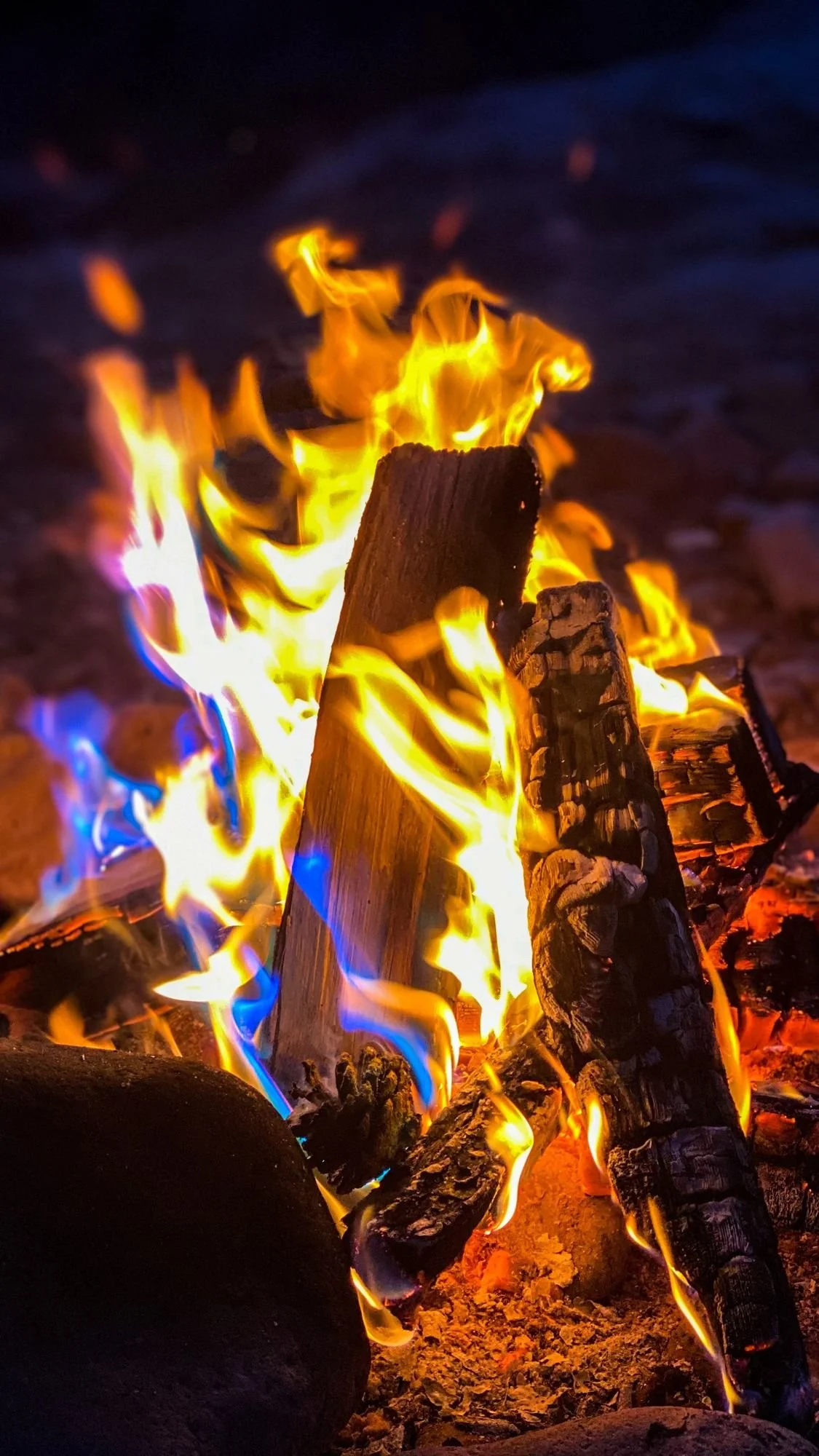 Close view of a roaring campfire with blue and orange flames on a spring road trip through Utah