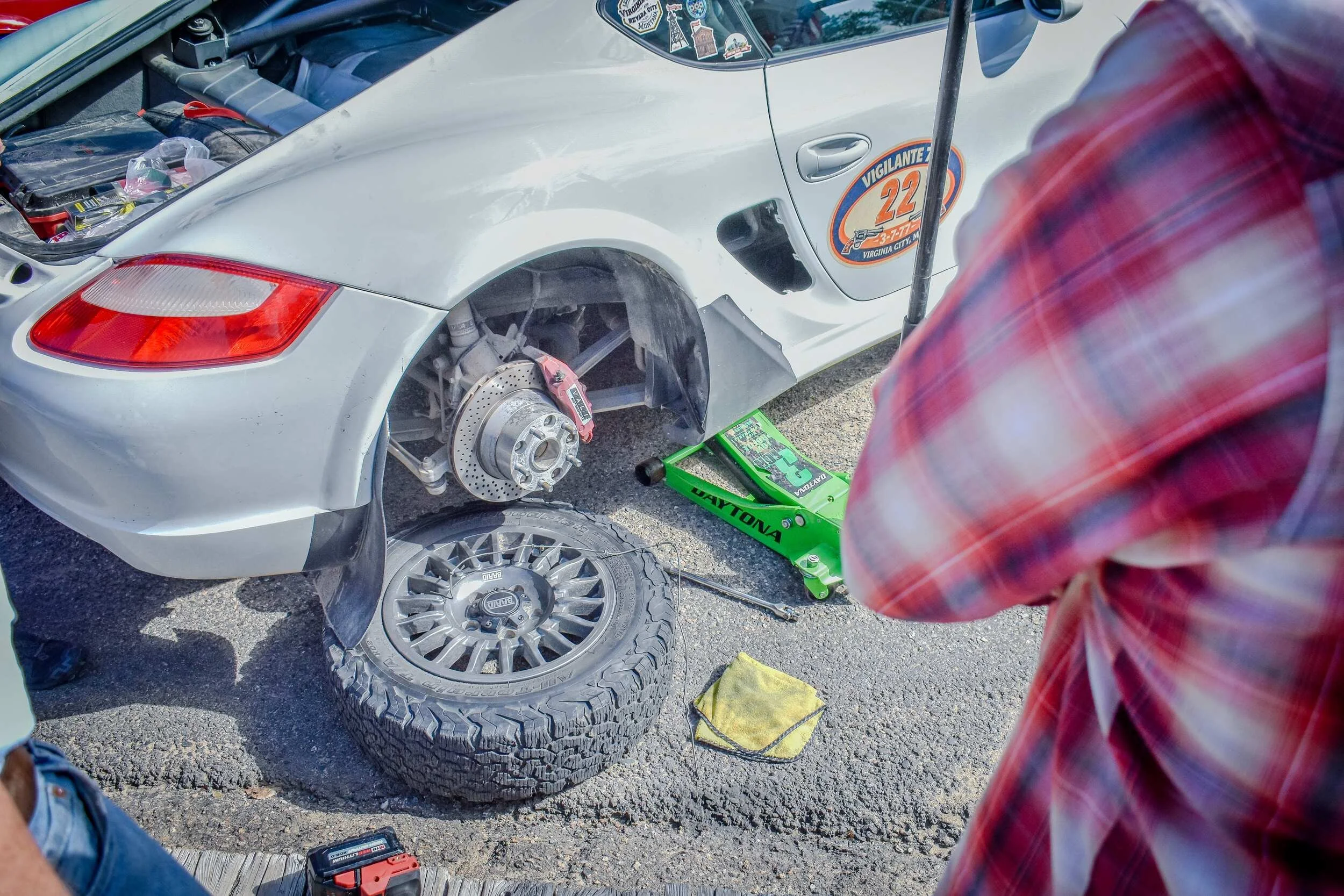 Nick repairing a white Porsche with its rear wheel removed after the Vigilante 77 Rally
