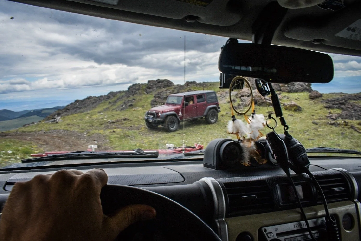 View through a windshield of a red Jeep on a grassy ridge in the Elkhorn Mountains near Boulder, Montana